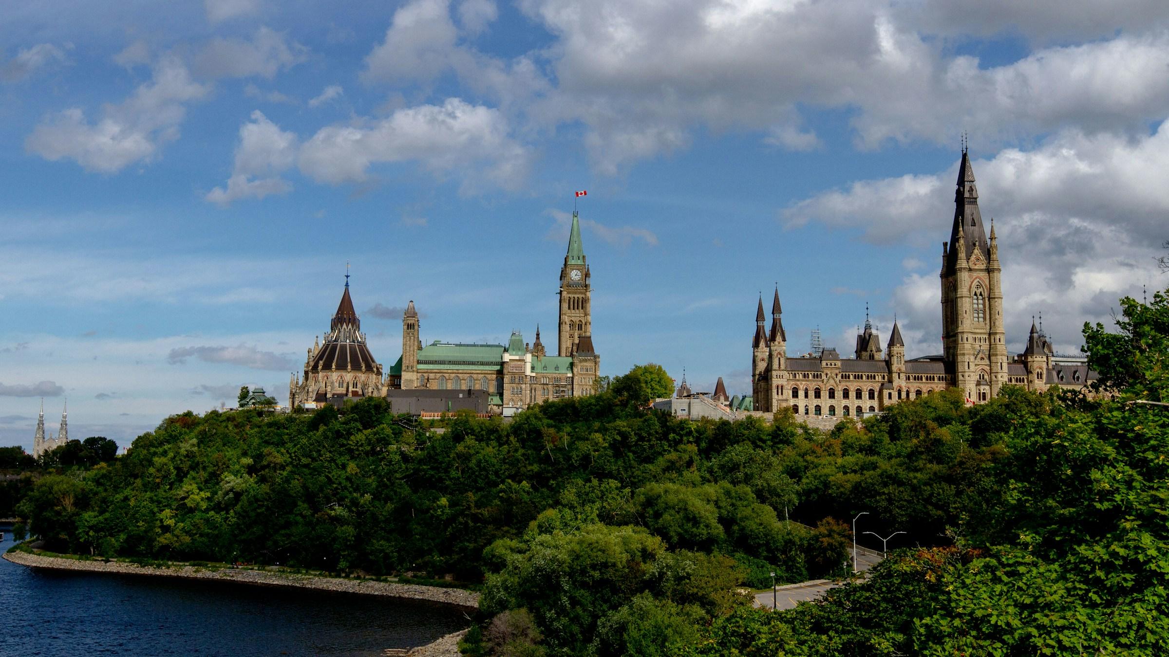 Parliament Hill in Ottawa, above the trees along the Ottawa River