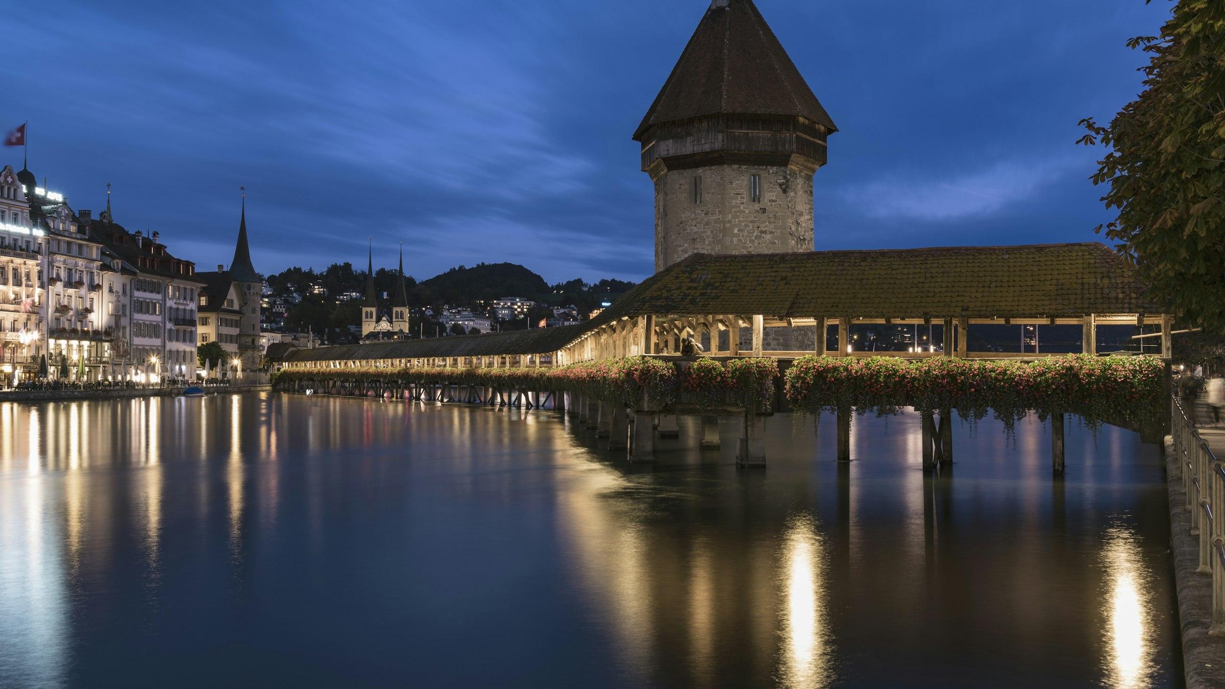 Lucerne's Chapel Bridge and Water Tower lit up on the Reuss at dusk, Switzerland