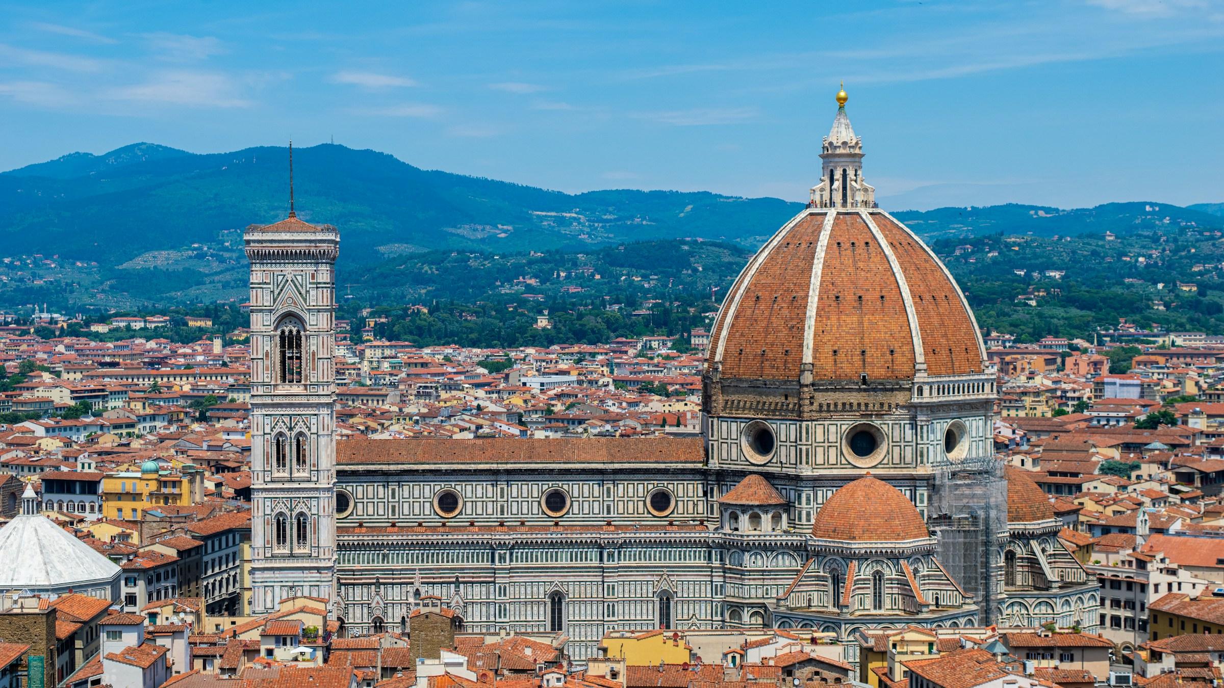 Florence Cathedral and its dome above the rooftops, with hills behind
