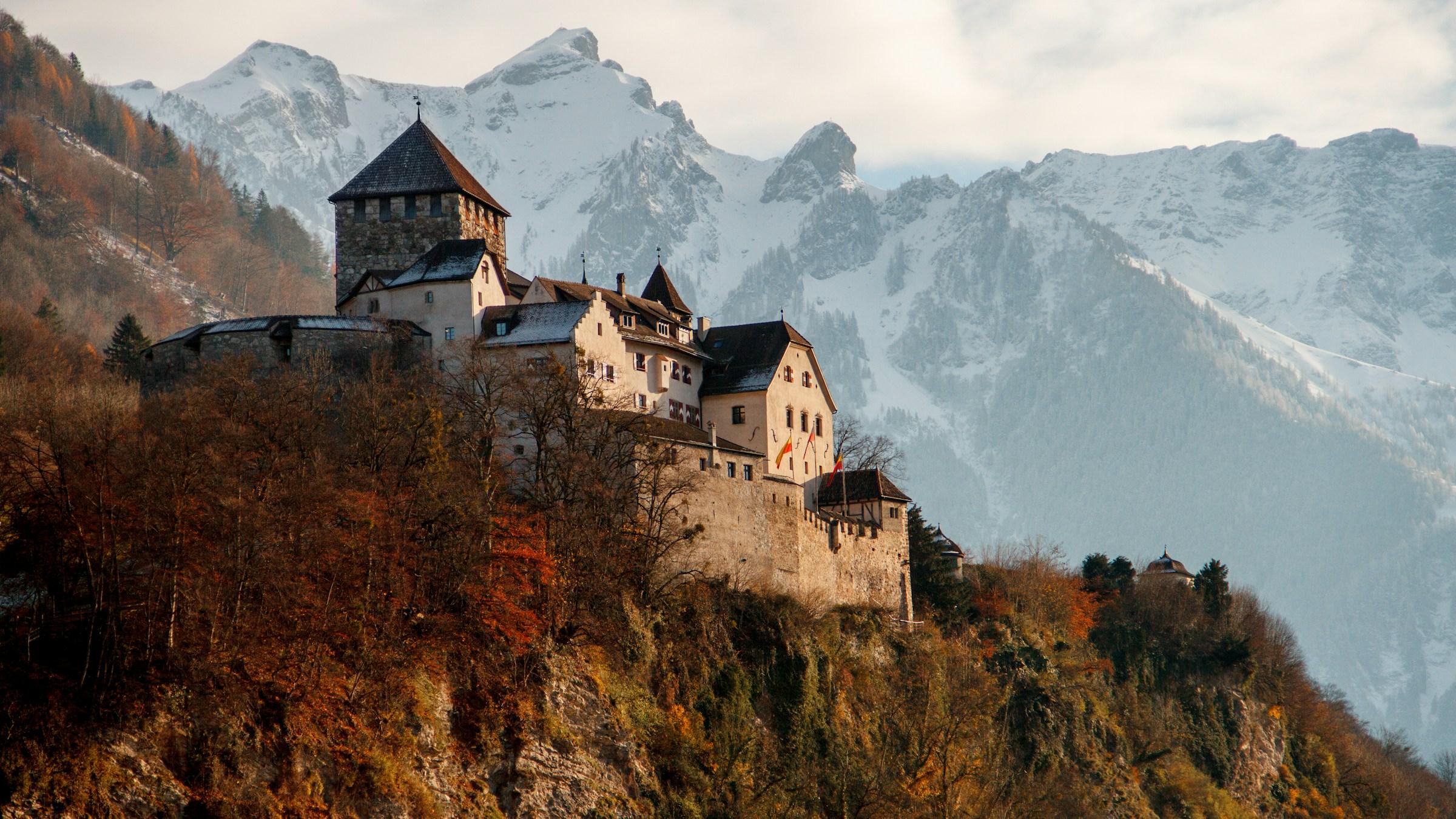 Vaduz Castle on its wooded cliff above Liechtenstein's capital, with snowy Alps behind
