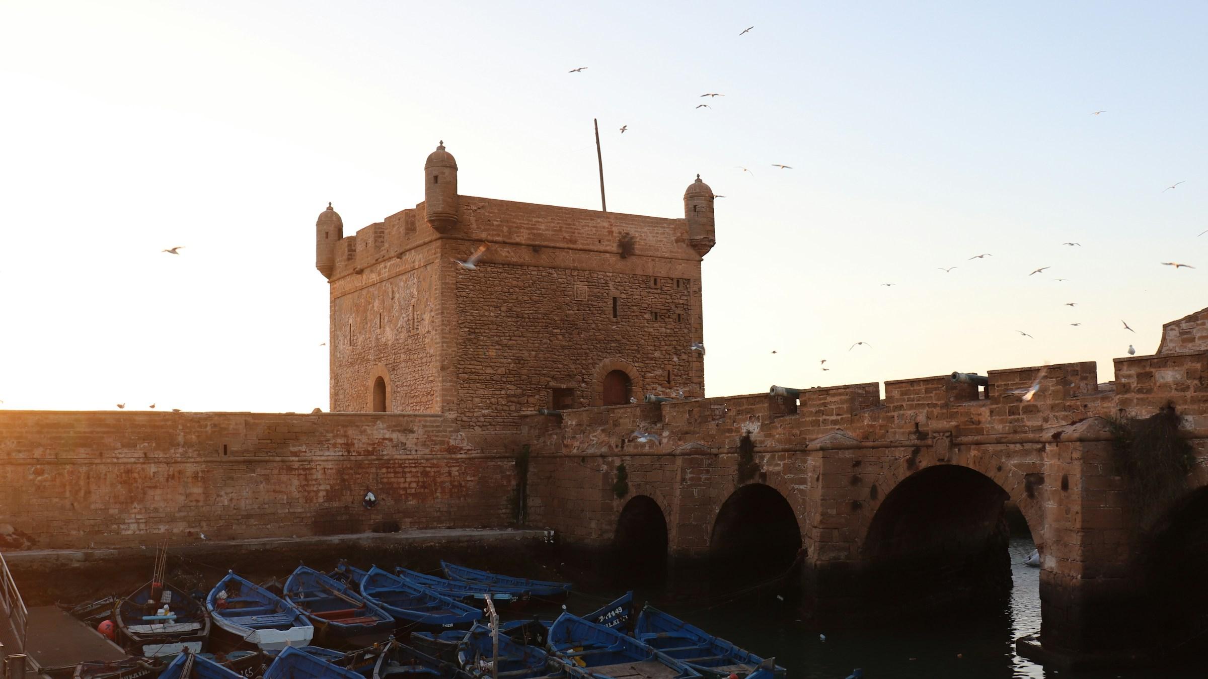 The Skala bastion and blue fishing boats in Essaouira at sunset
