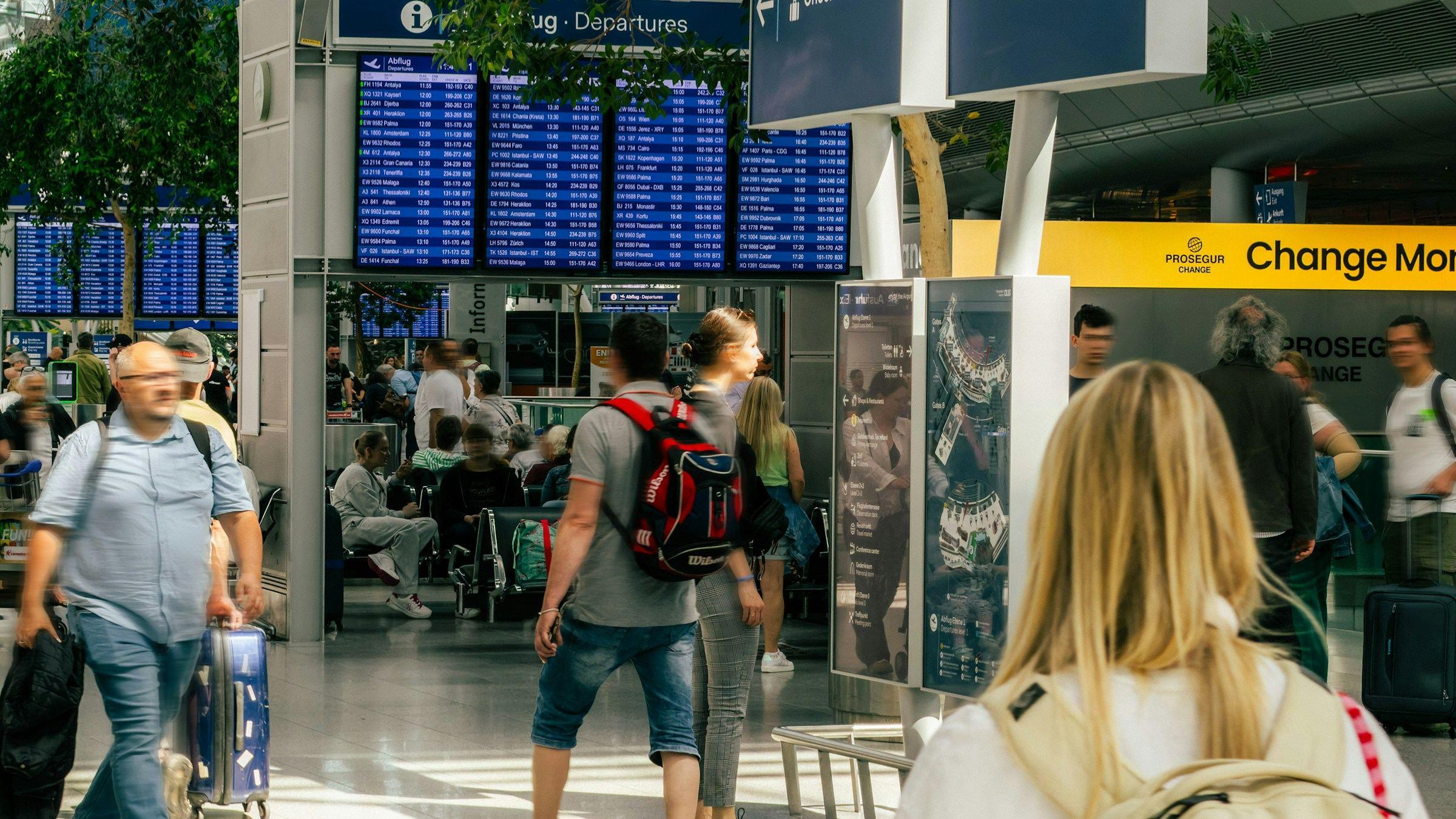 Travellers walking past flight departure boards in an airport terminal