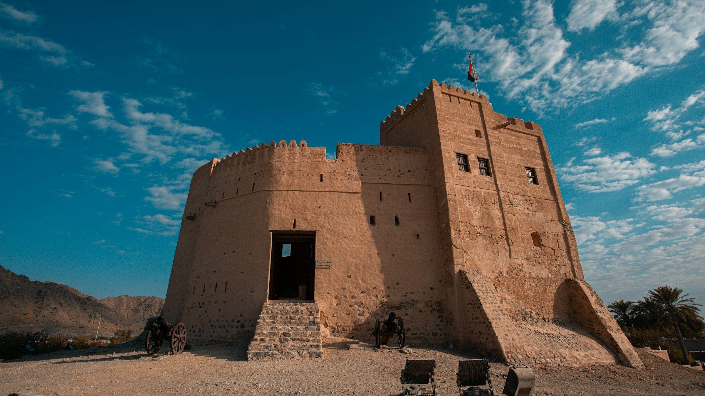 The mud-brick walls and towers of Fujairah Fort under a blue sky