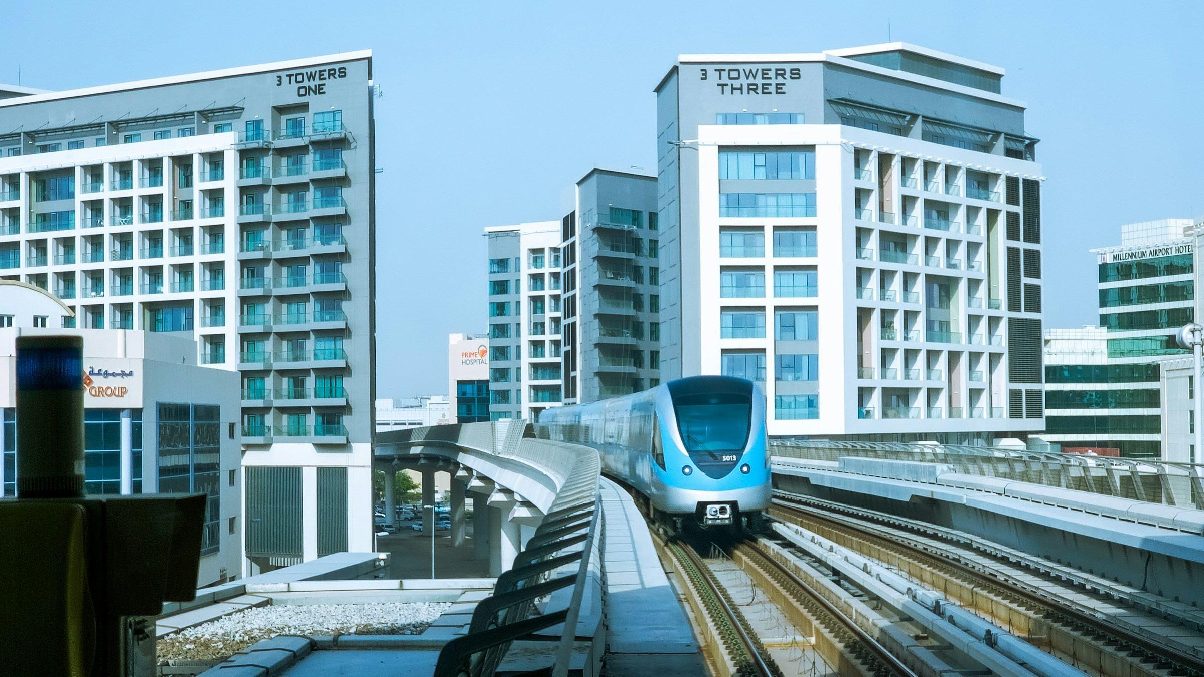 A Dubai Metro train on the elevated Red Line, passing hotel towers