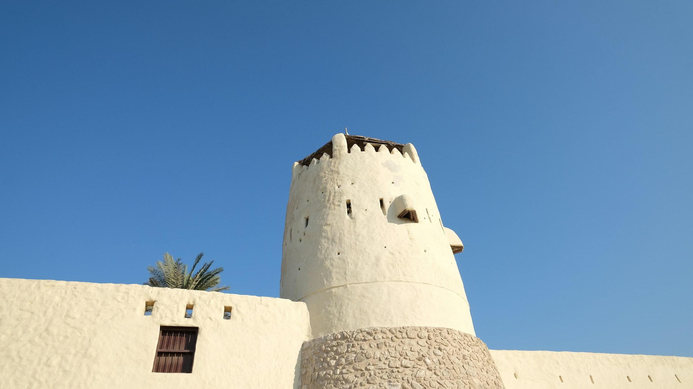 The white tower of Umm Al Quwain Fort against a clear blue sky