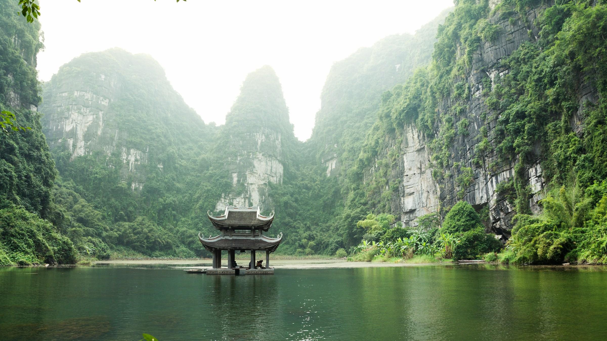 A pagoda on the water among limestone cliffs at Trang An, Ninh Binh