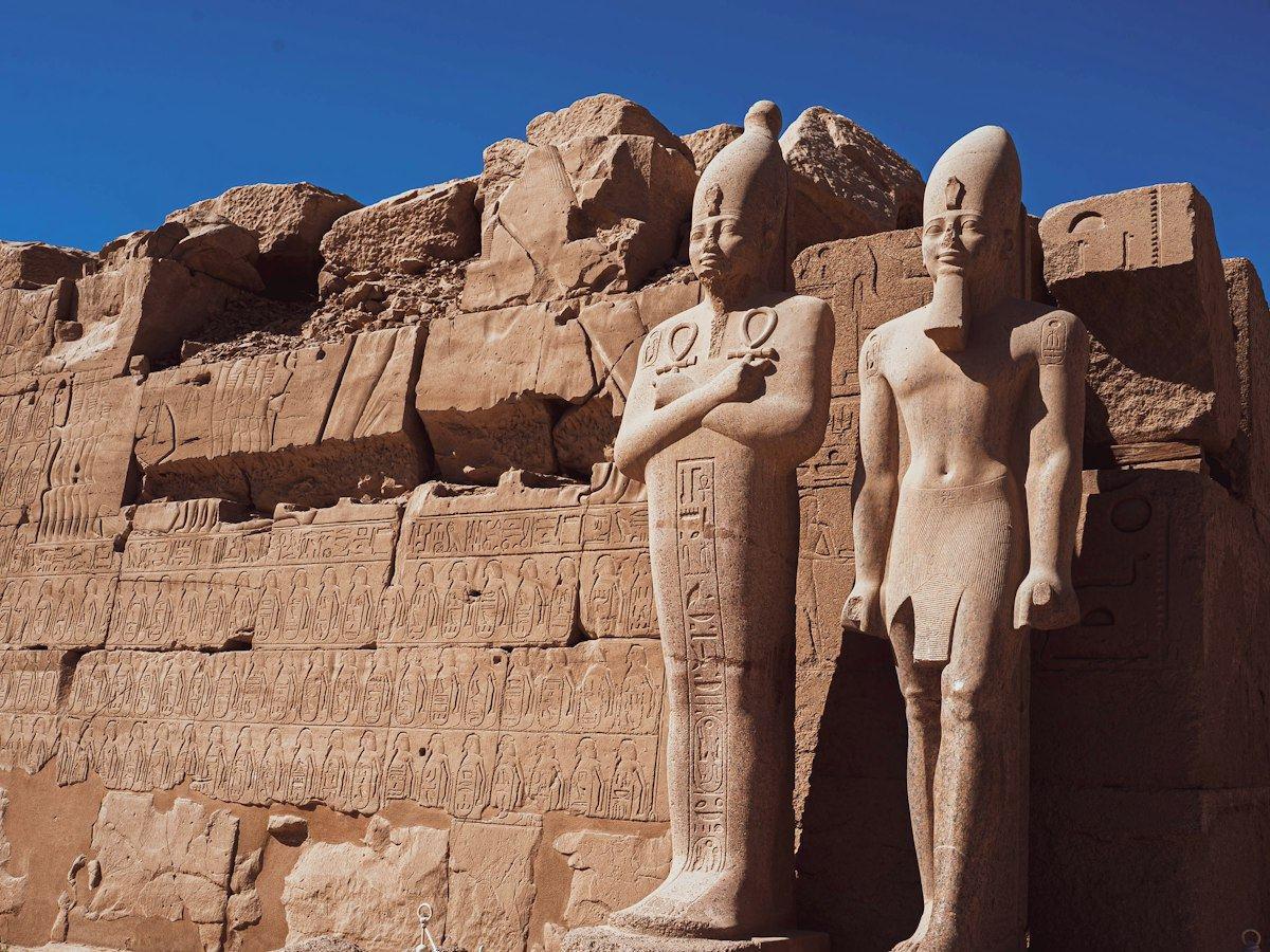 تماثيل فرعونية قائمة أمام الجدران الحجرية المنحوتة لمعابد الكرنك في الأقصر