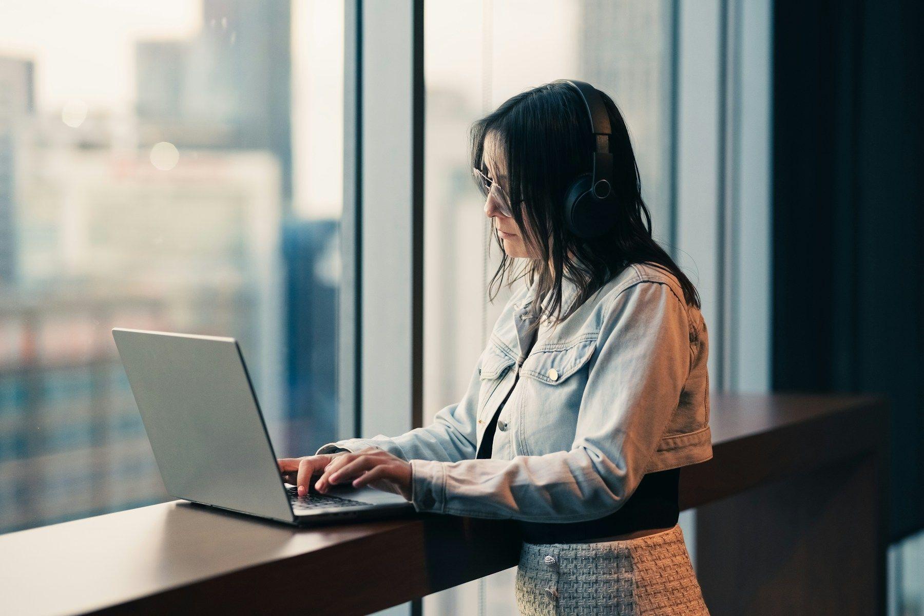 A freelancer working on a laptop at a window counter in a high-rise