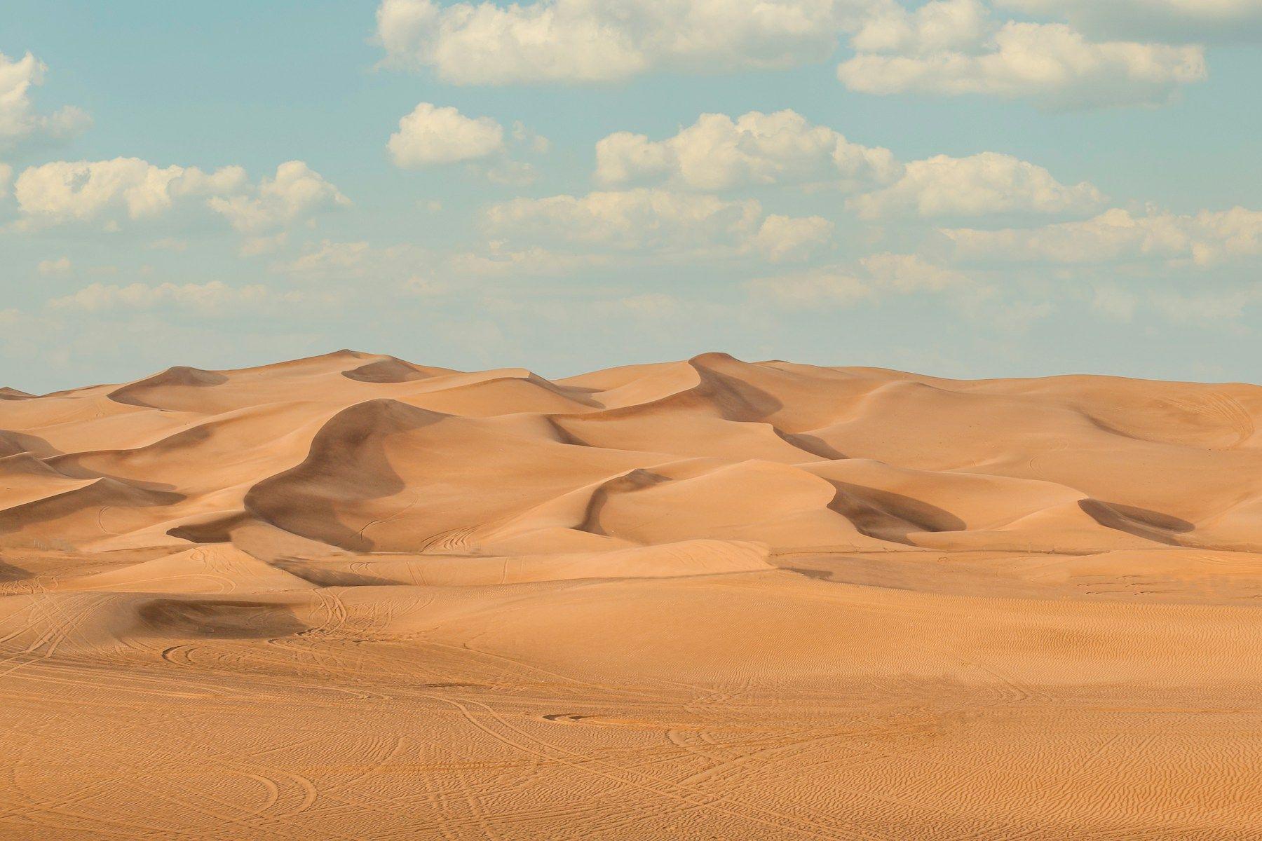 Wind-shaped sand dunes in the UAE desert under a blue sky