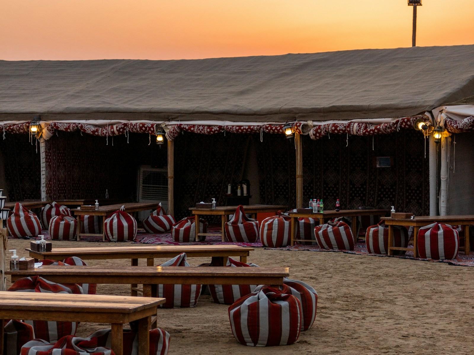 Tables and cushioned seating set out at a desert camp near Dubai
