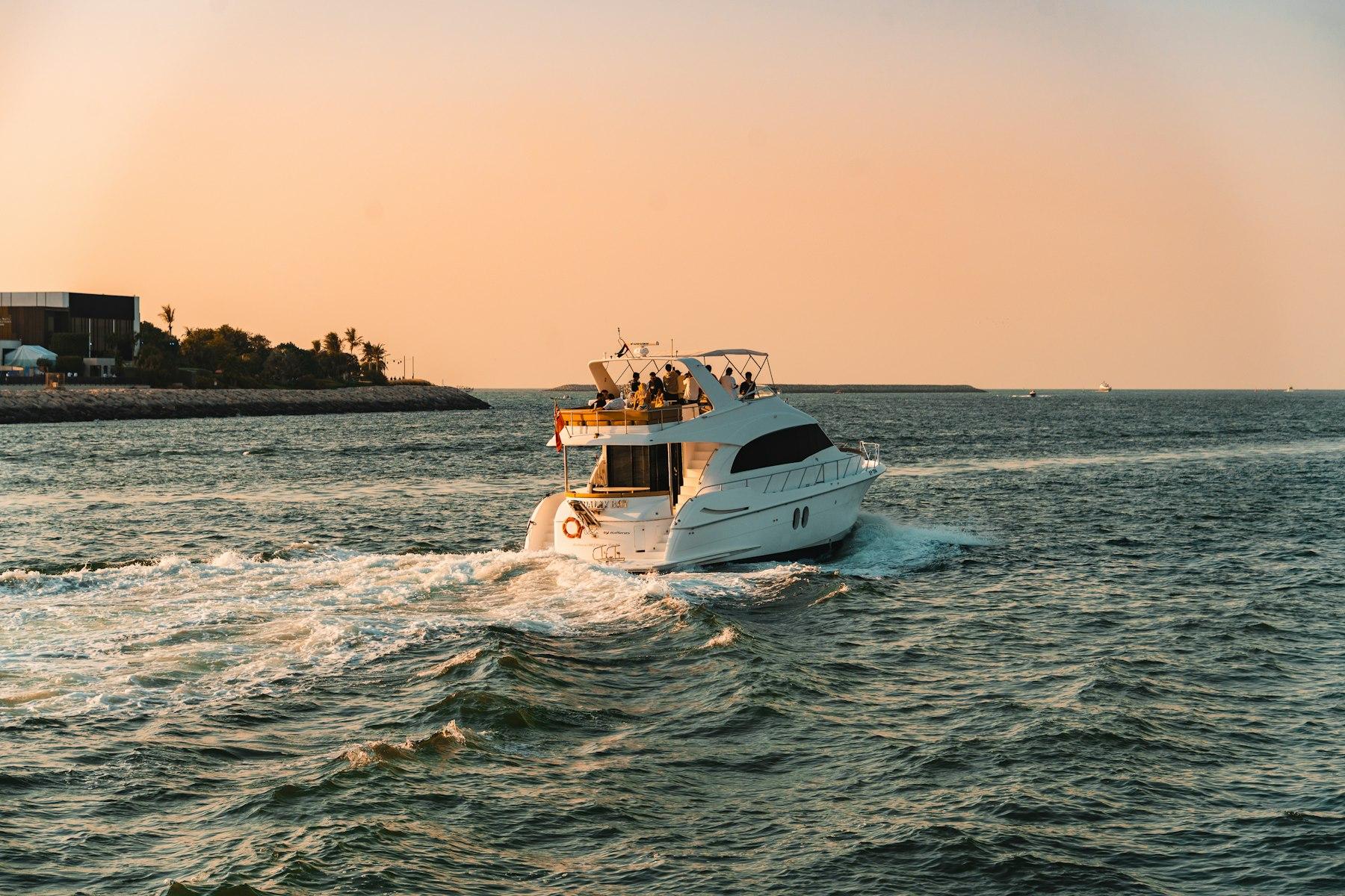 A yacht heading out to sea off Dubai Marina at sunset