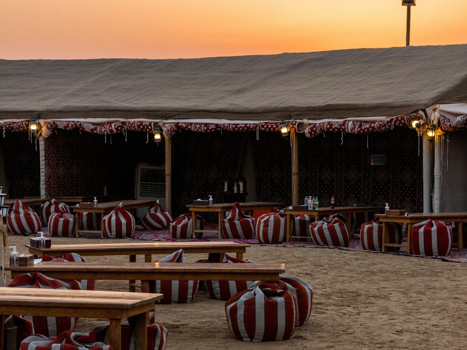 Tables and cushioned seating set out at a desert camp near Dubai