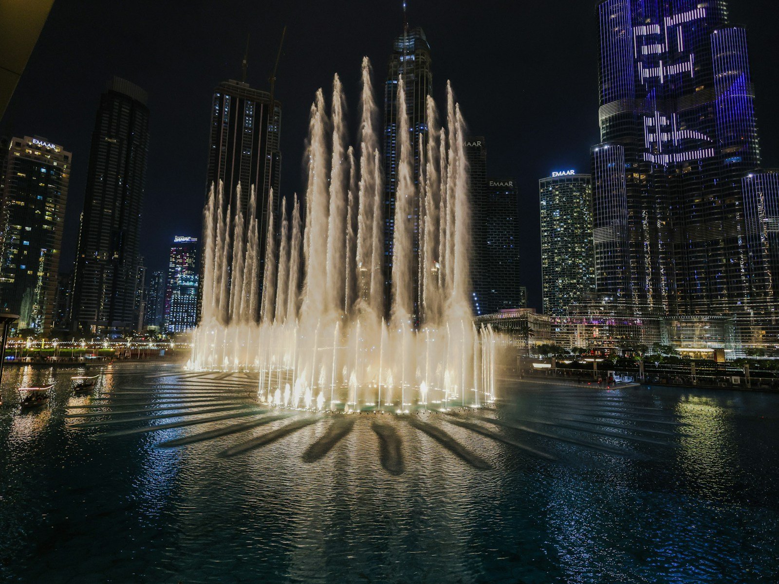 The Dubai Fountain lit up at night beside The Dubai Mall