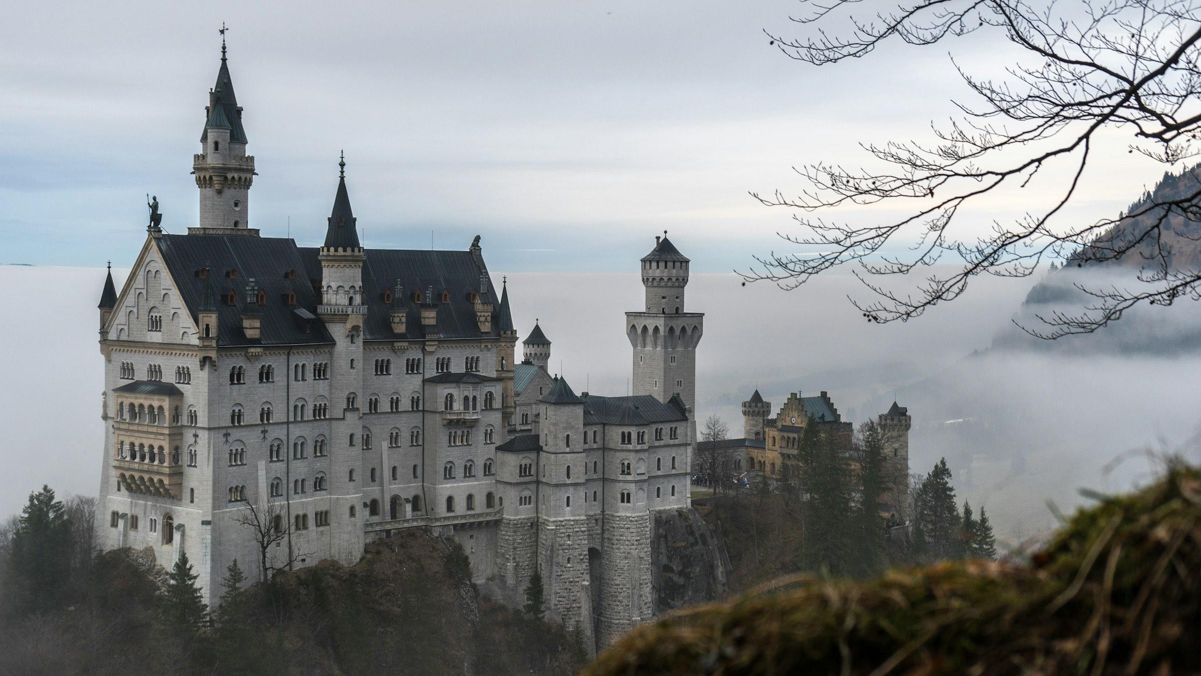 Neuschwanstein Castle above the Bavarian forest on a misty morning