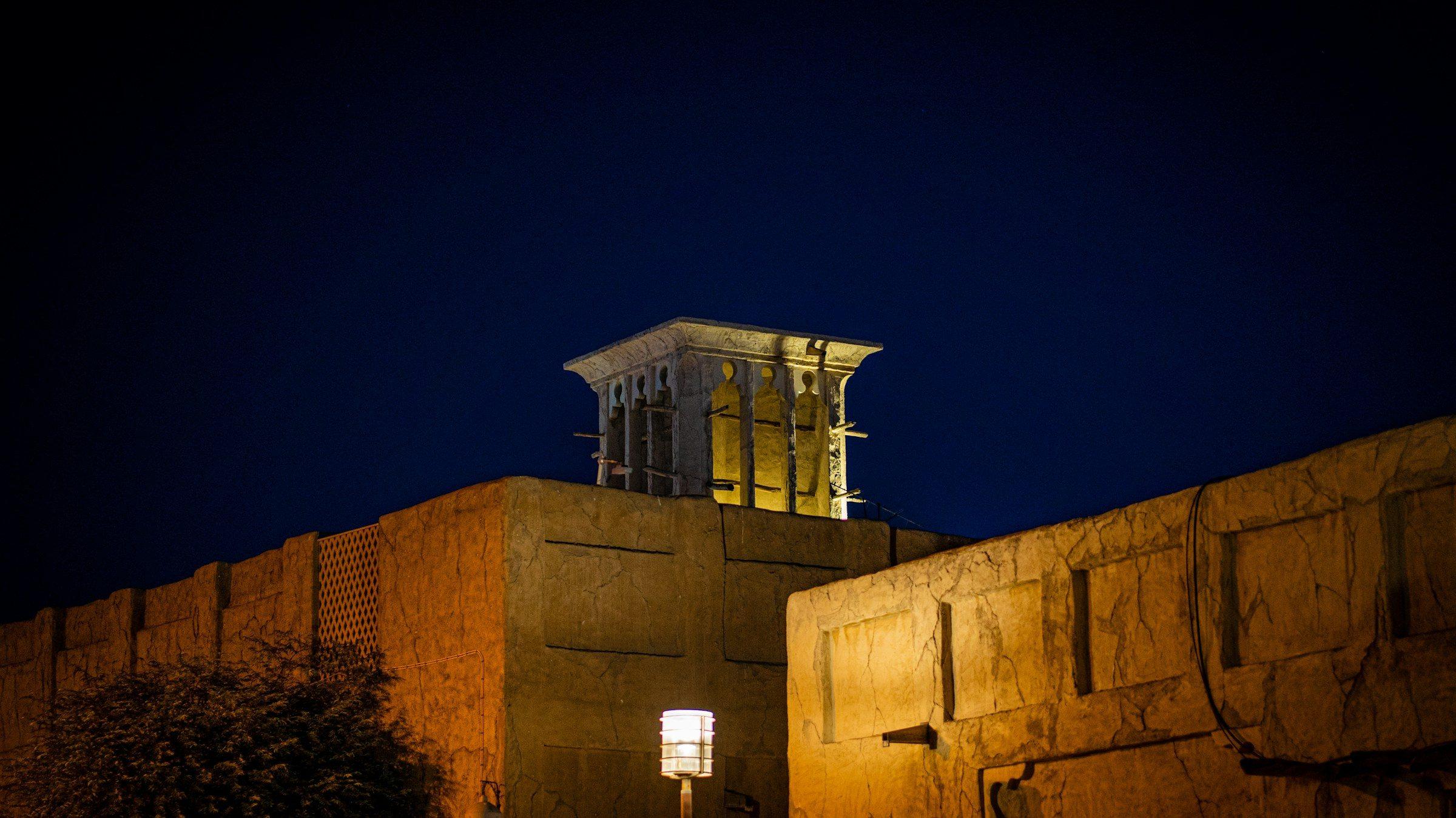 The wind tower of a heritage house in Dubai's Al Fahidi district, lit at night