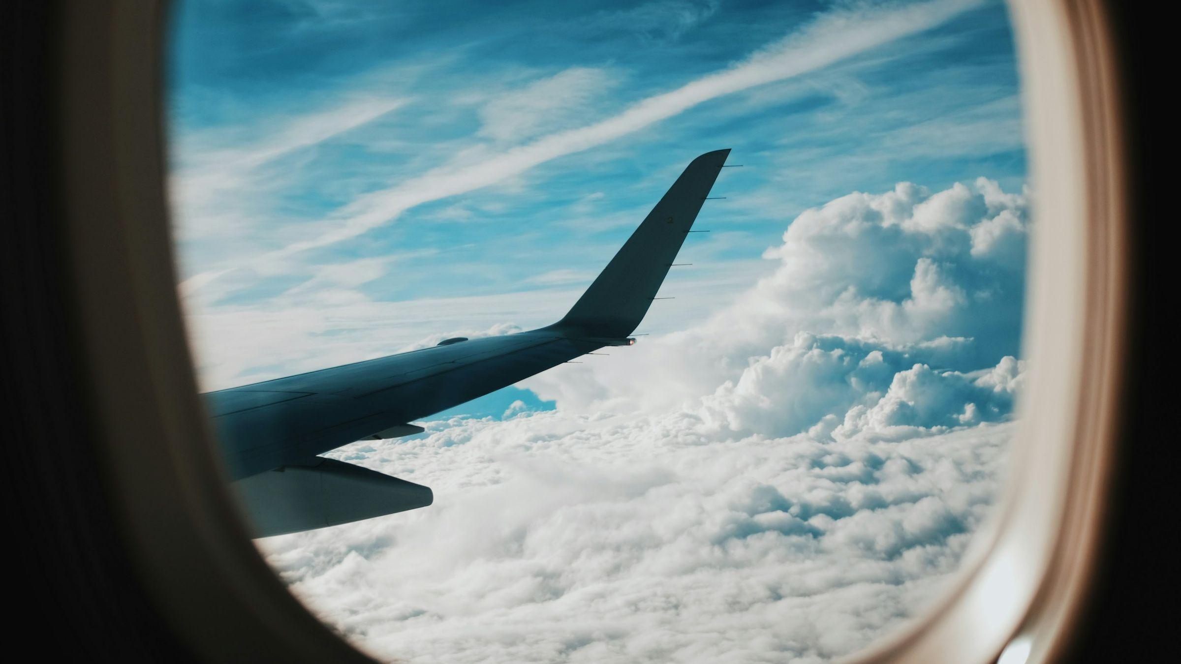 An aircraft wing above the clouds, seen from a window seat