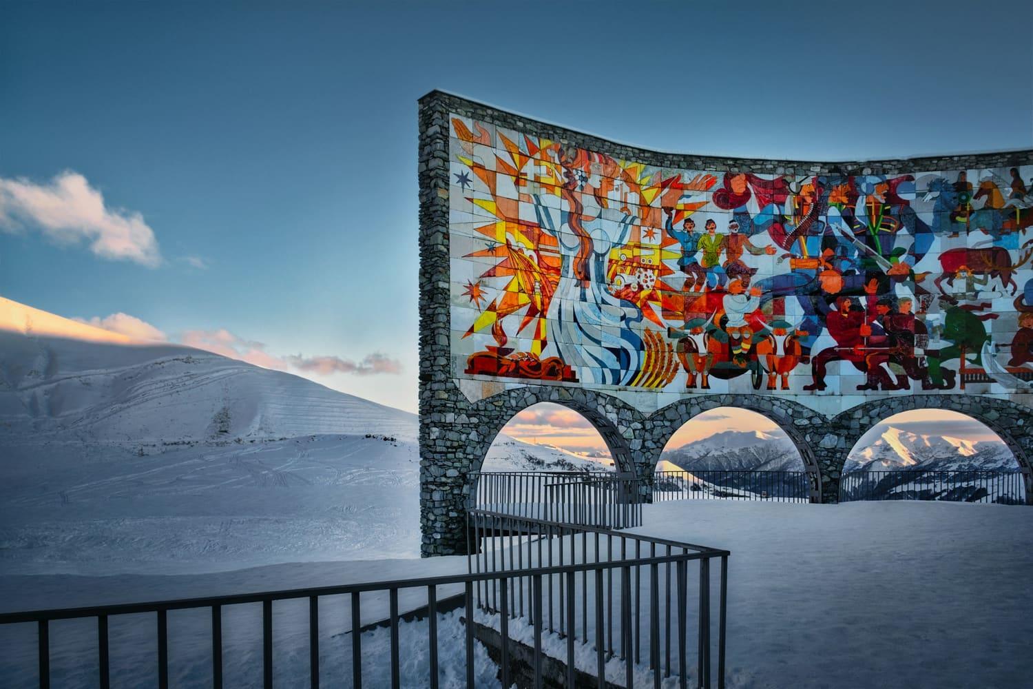 The mosaic arch of the Friendship Monument above the snow at Gudauri