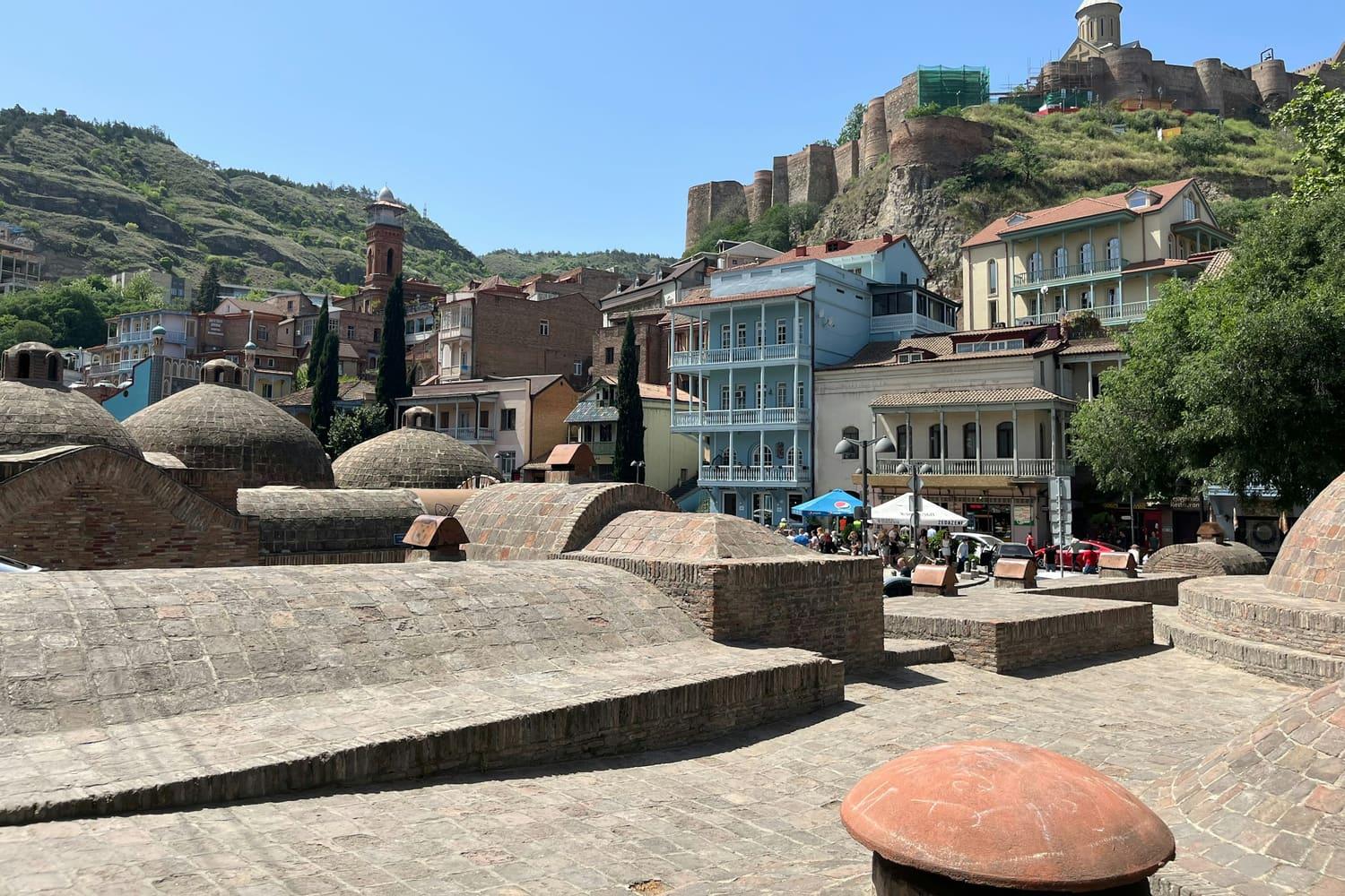 The brick domes of the Abanotubani sulphur baths in Tbilisi, with Narikala Fortress on the hill above