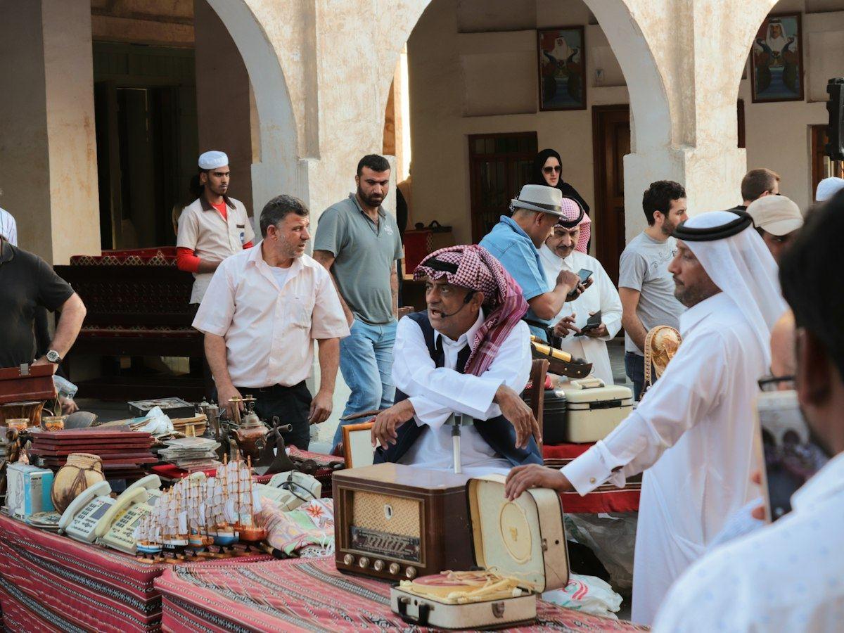 تجار ومتسوقون عند كشك للتحف في سوق واقف بالدوحة