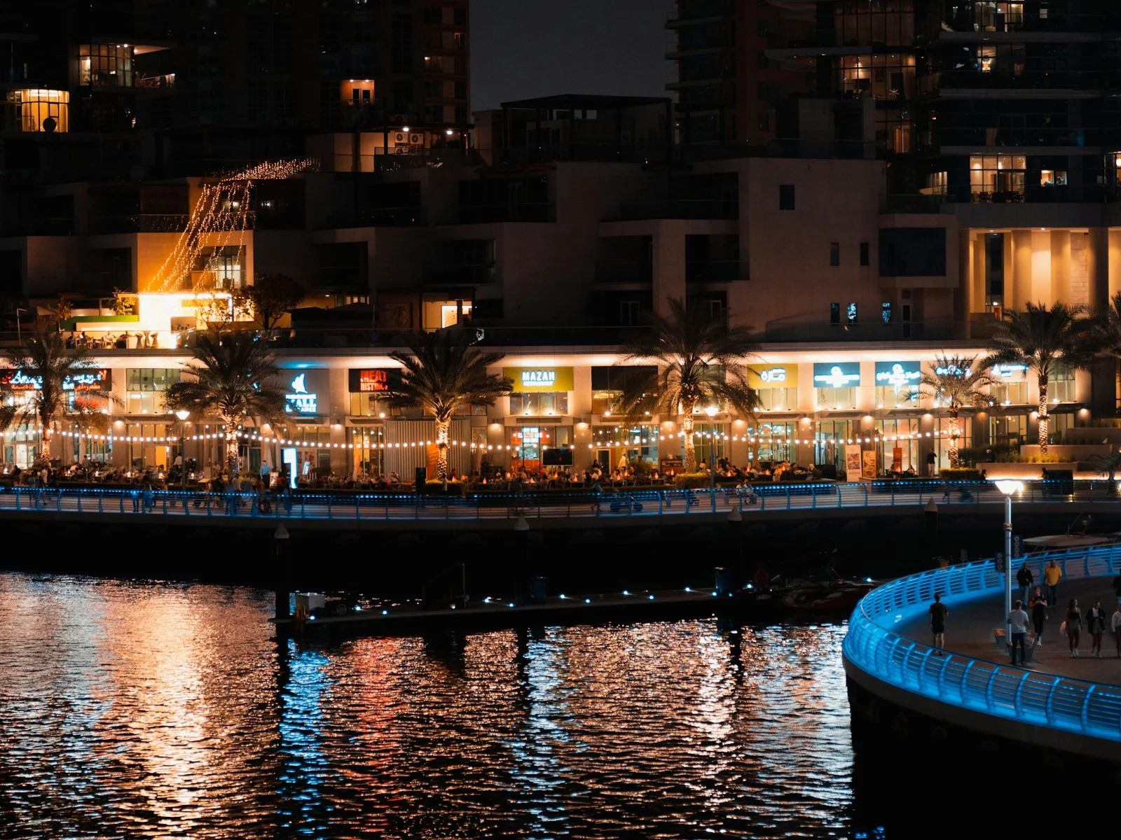 مطاعم مضاءة على طول ممشى دبي مارينا ليلا