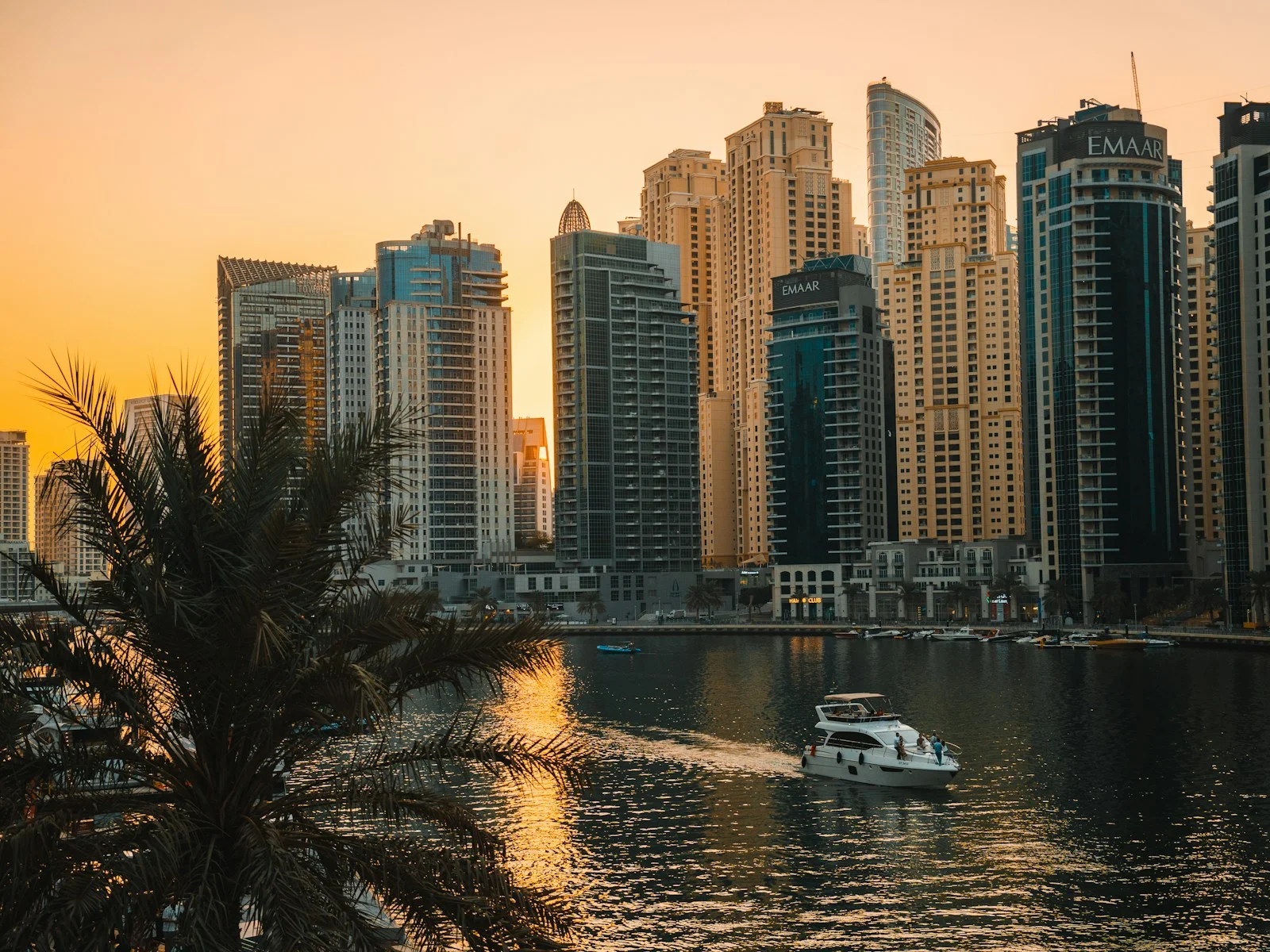 A boat crossing Dubai Marina at sunset, past the towers