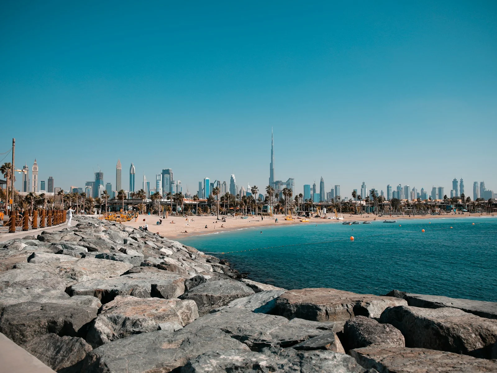 شاطئ عام في دبي، وتظهر خلفه أفق المدينة عبر الماء