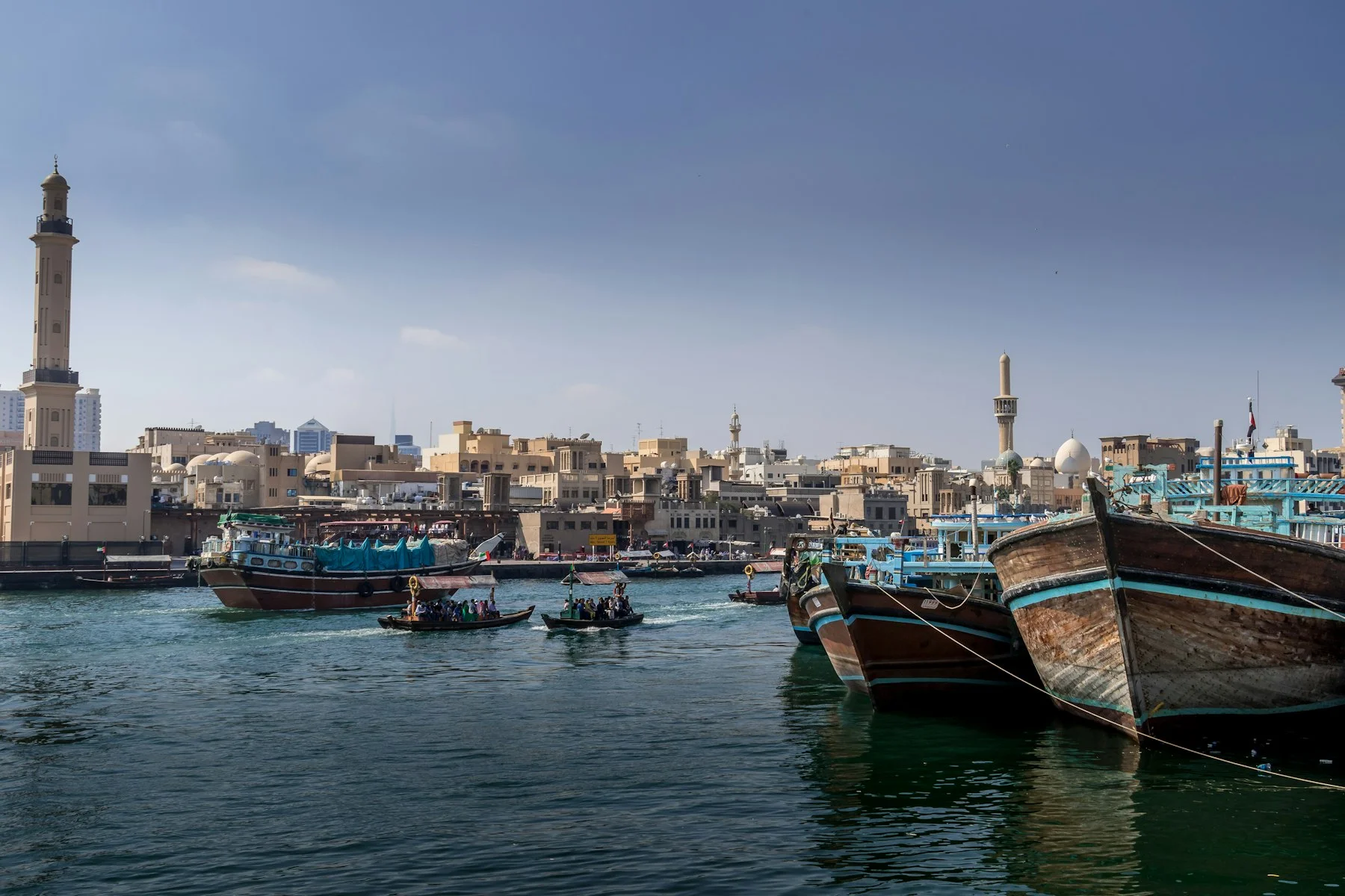 عبرات تعبر خور دبي بجانب قوارب داو خشبية راسية