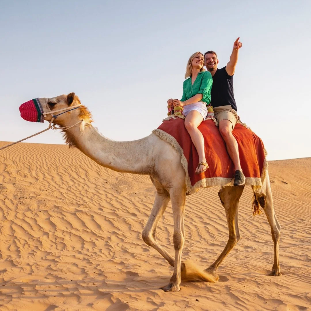 زوجان يركبان جملا في الصحراء