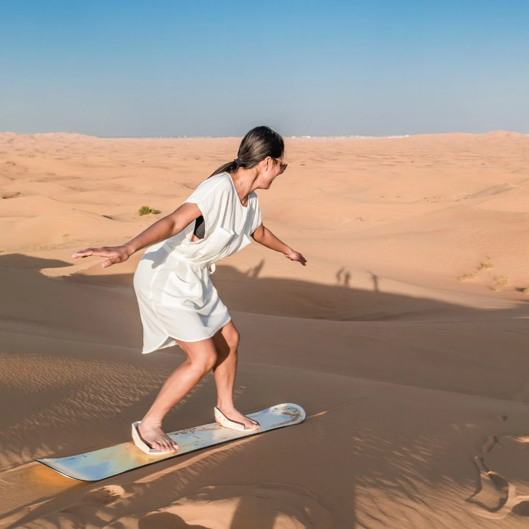 Sandboarding down a dune on the desert safari