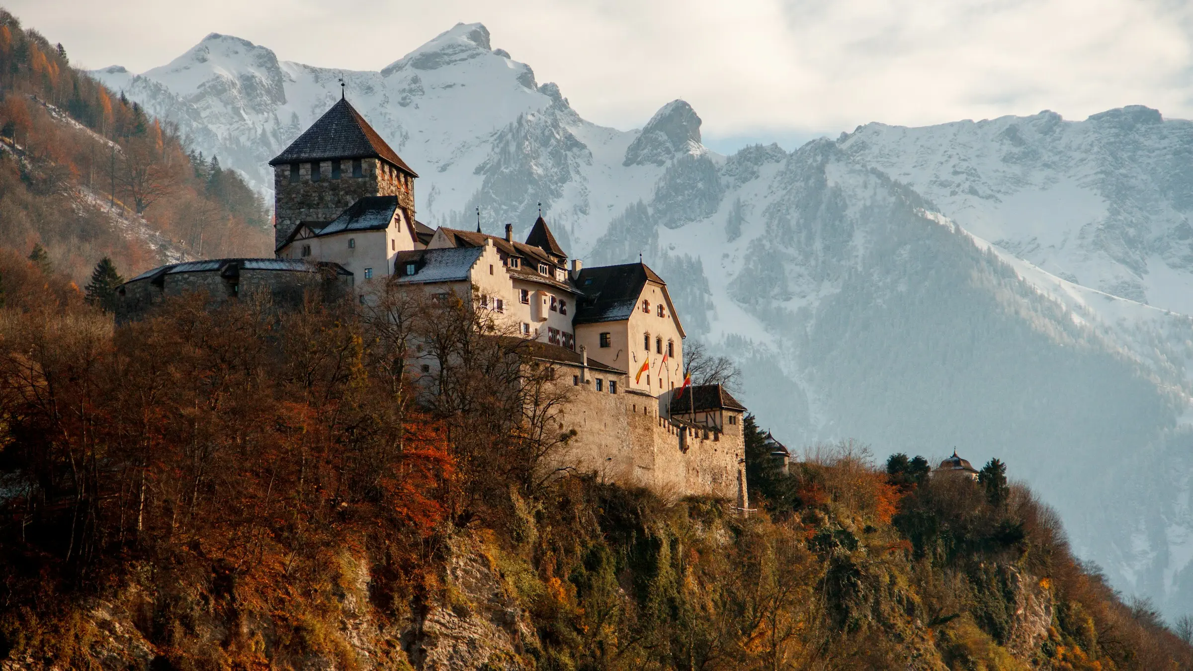 Vaduz Castle on its wooded cliff above Liechtenstein's capital, with snowy Alps behind