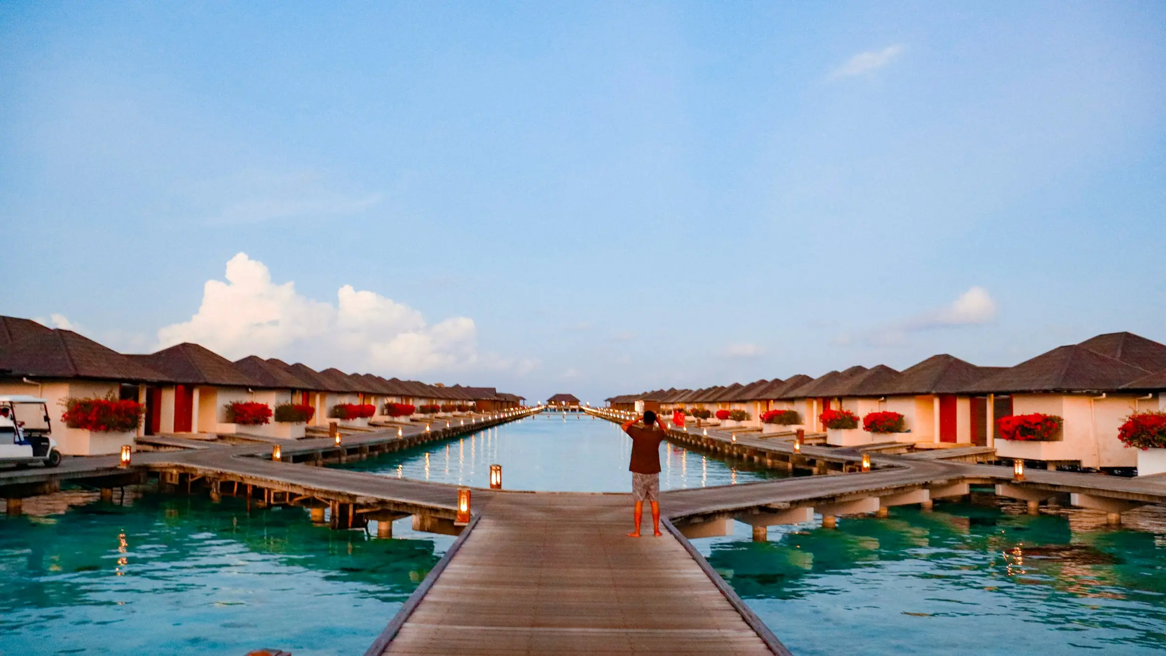 Overwater villas along a lantern-lit jetty in the Maldives at dusk