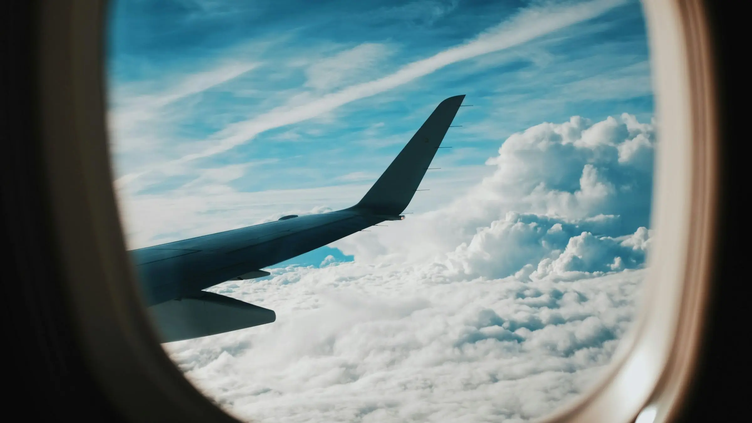 An aircraft wing above the clouds, seen from a window seat