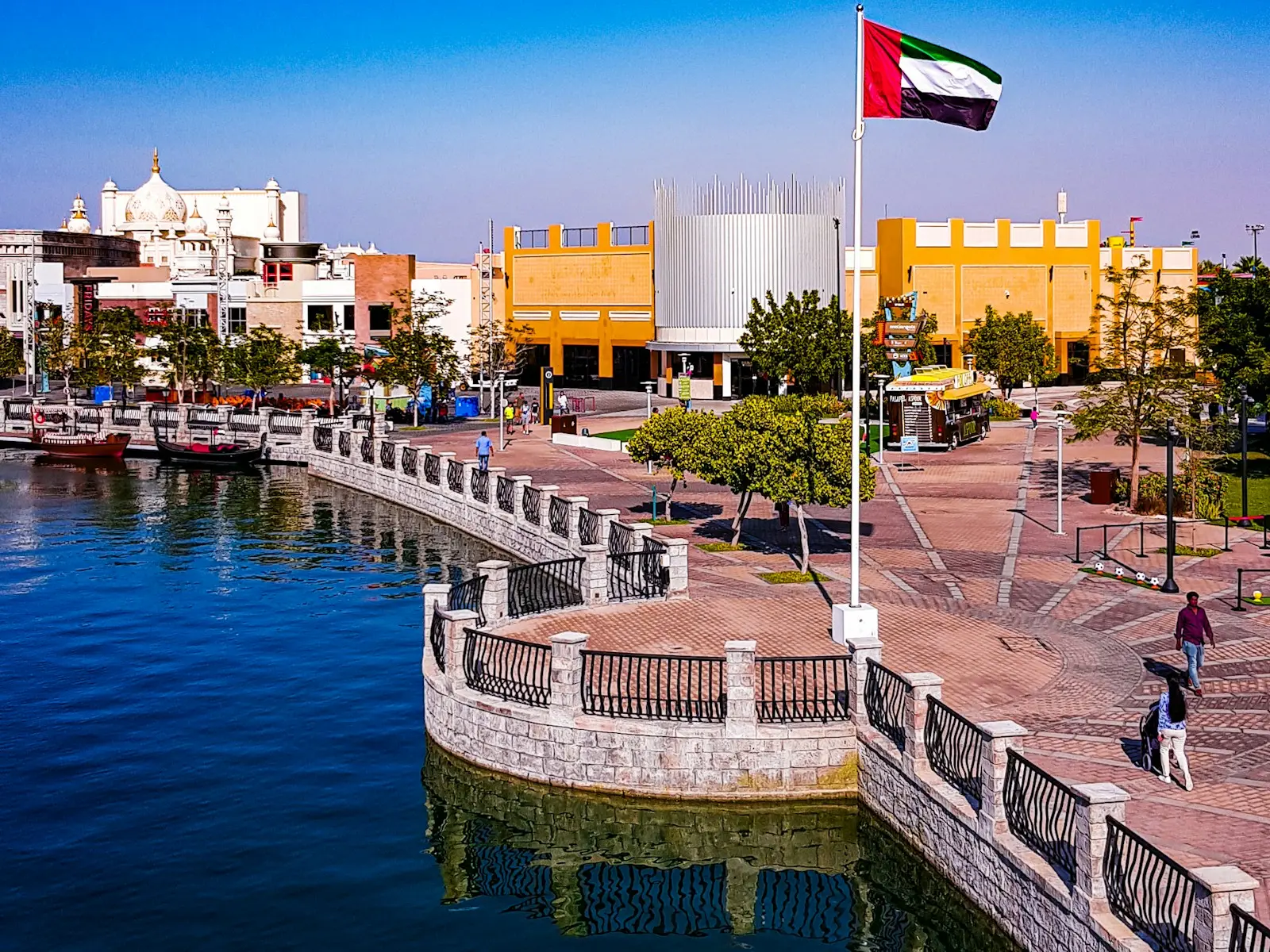 Riverland's canal-side promenade and a UAE flag at Dubai Parks and Resorts