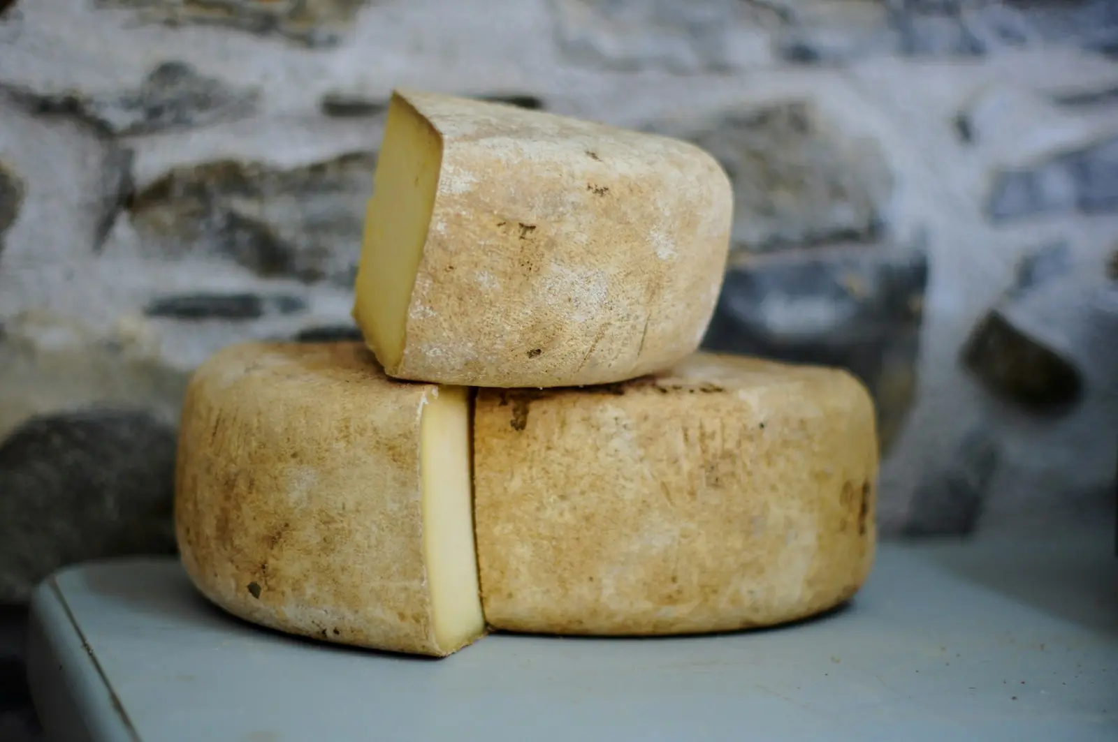 Wheels of Dutch cheese stacked on a stone shelf