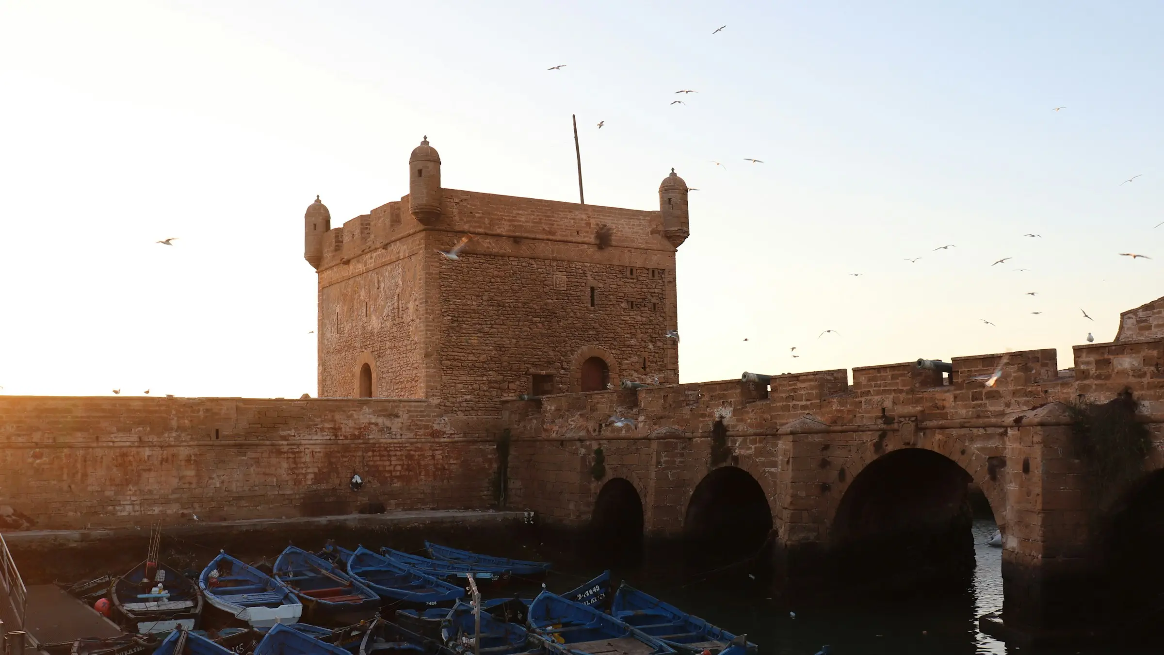 The Skala bastion and blue fishing boats in Essaouira at sunset