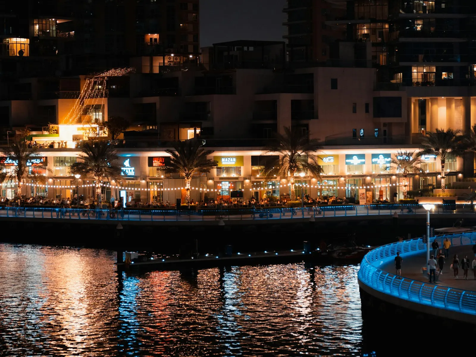 مطاعم مضاءة على طول ممشى دبي مارينا ليلا