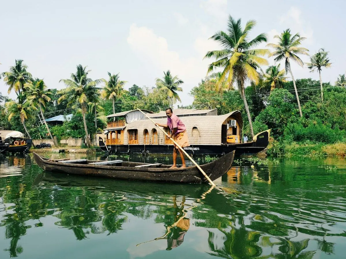 A houseboat and a small boat among palms on the Kerala backwaters near Alappuzha