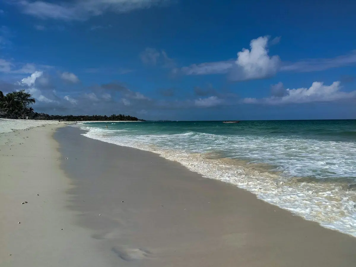 An empty stretch of white sand and surf at Diani Beach