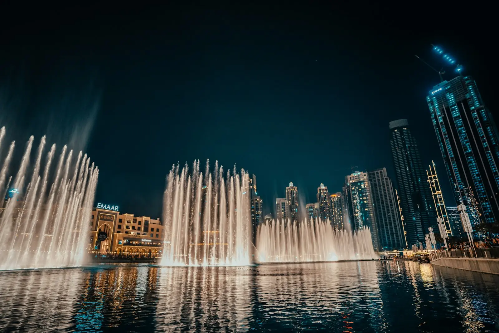 نفثات النافورة مضاءة ليلا أسفل أبراج وسط مدينة دبي