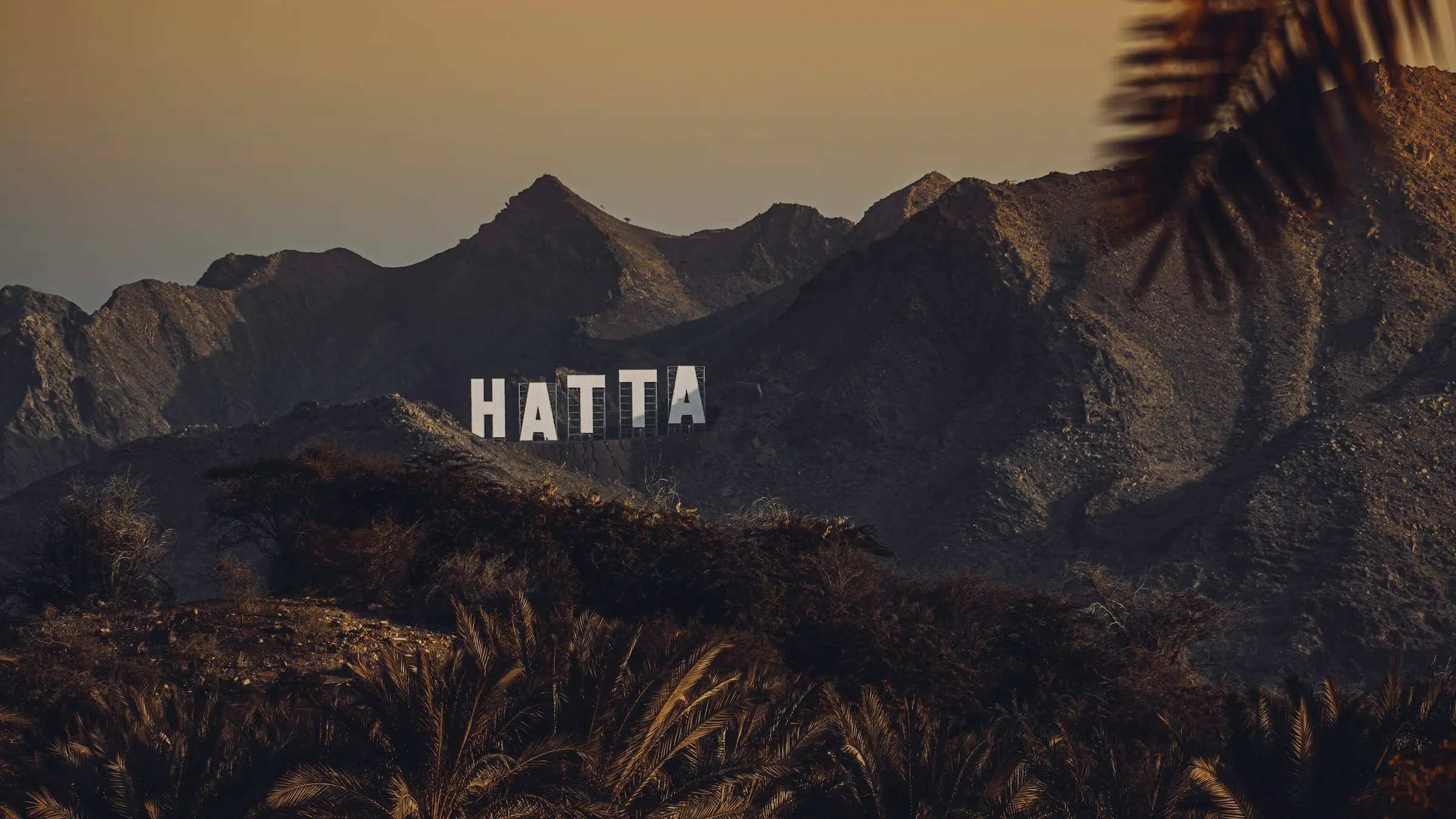 The HATTA sign on a hilltop at sunset