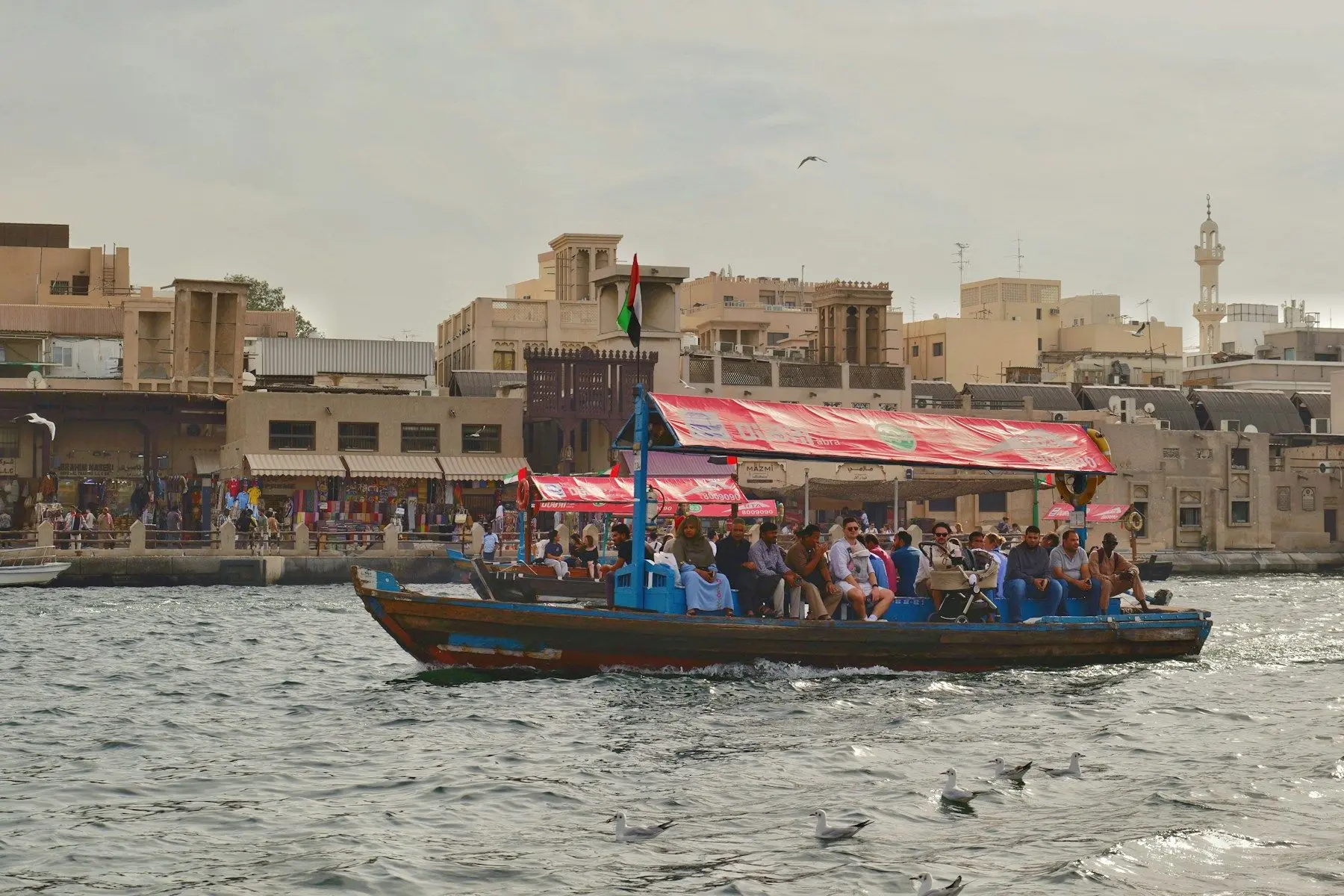 An abra water taxi full of passengers crossing Dubai Creek