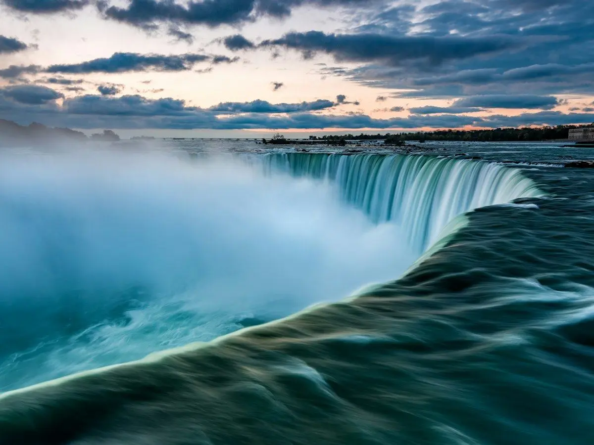 Niagara Falls pouring over its curved edge at sunrise