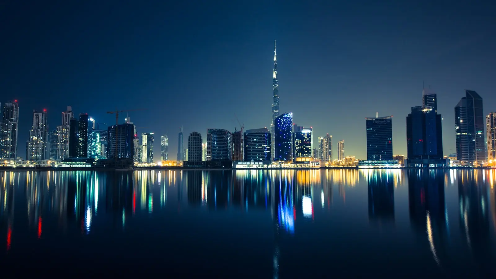 Downtown Dubai's skyline at night, with Burj Khalifa lit up and reflected in the water