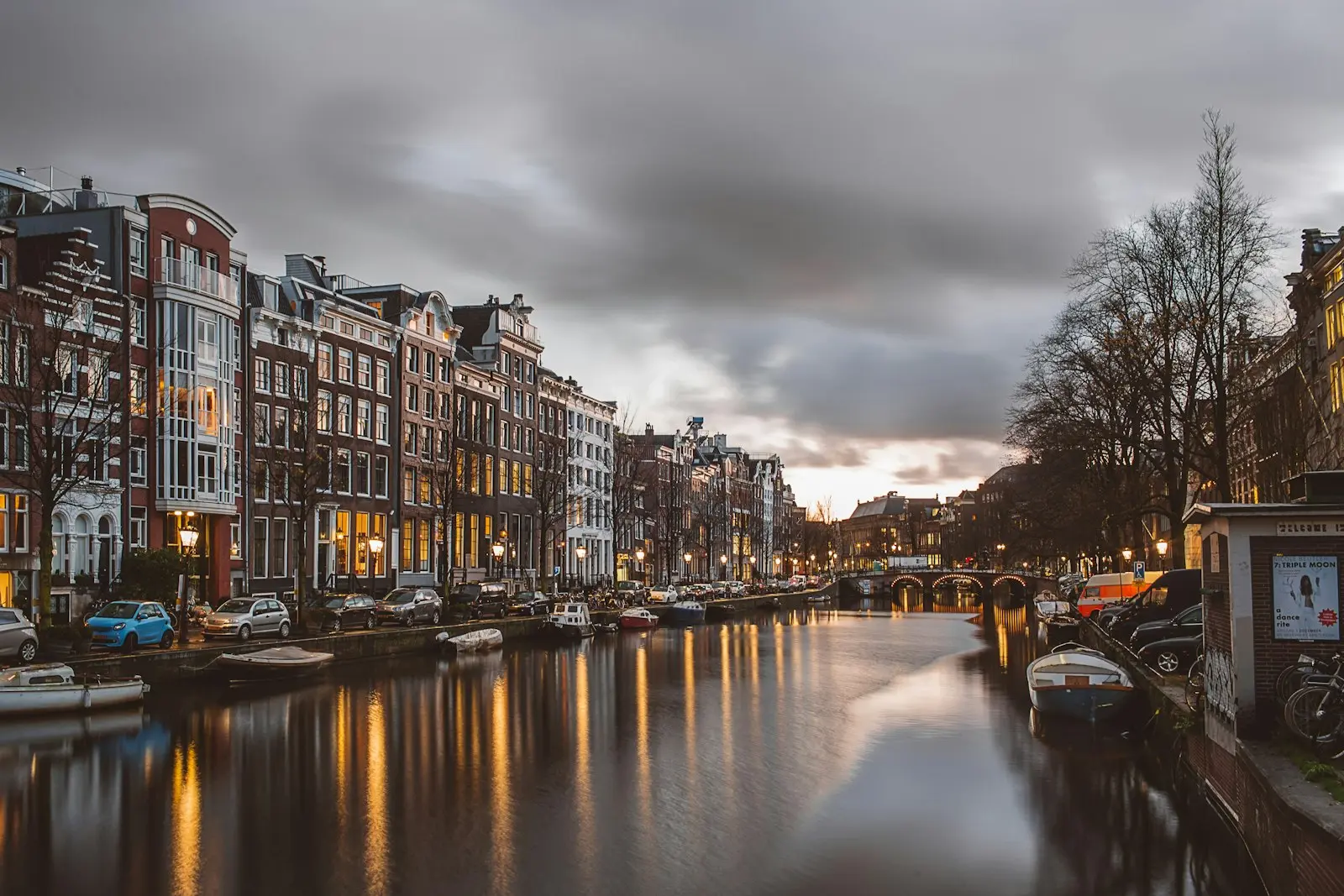 Canal houses lit up along an Amsterdam canal at dusk