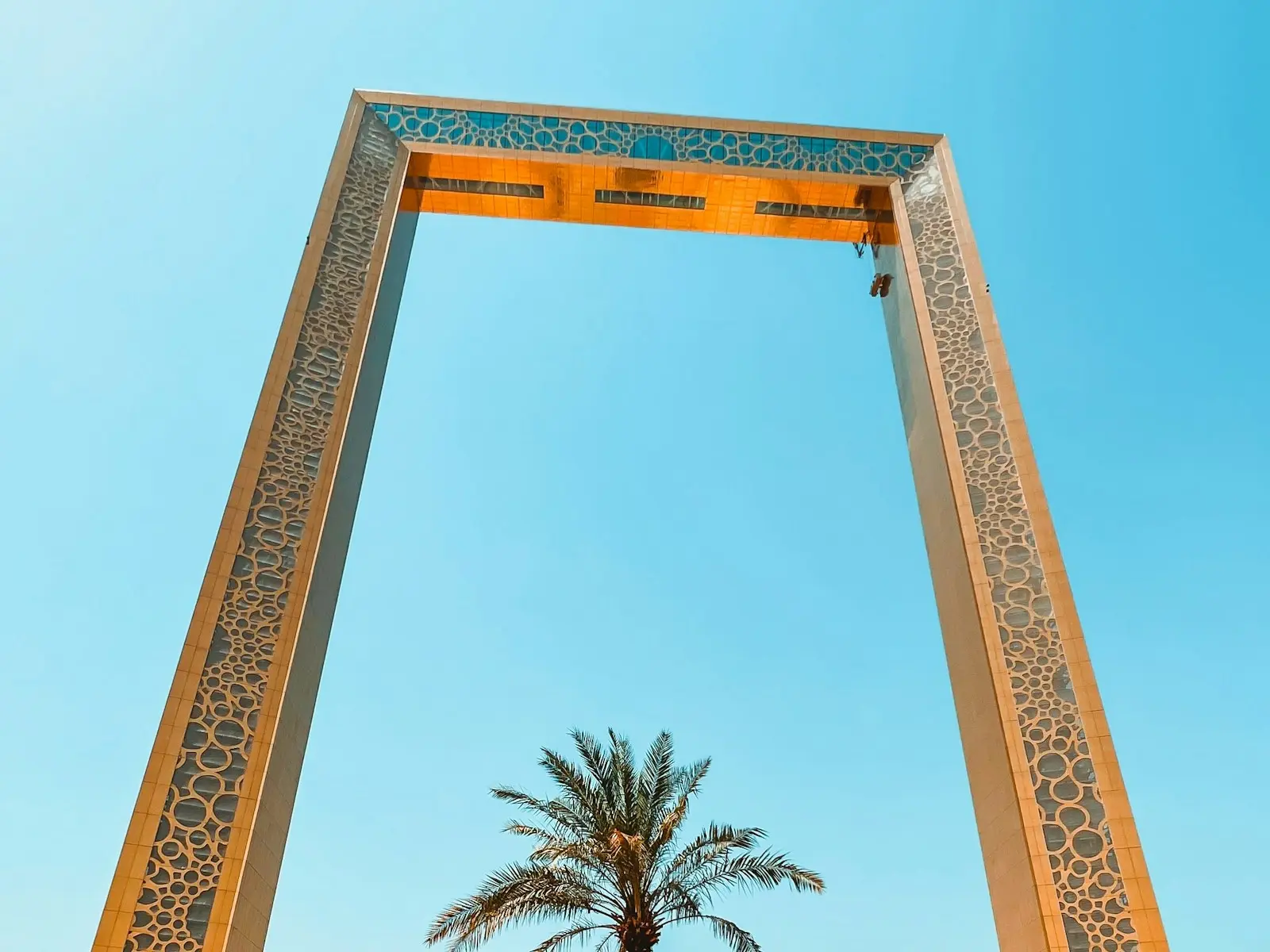 برواز دبي تحت سماء صافية، مع نخلة أسفله