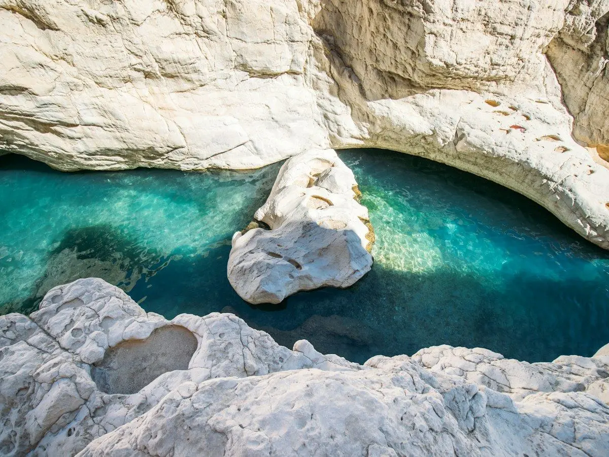 Turquoise water winding between white rocks at Wadi Bani Khalid