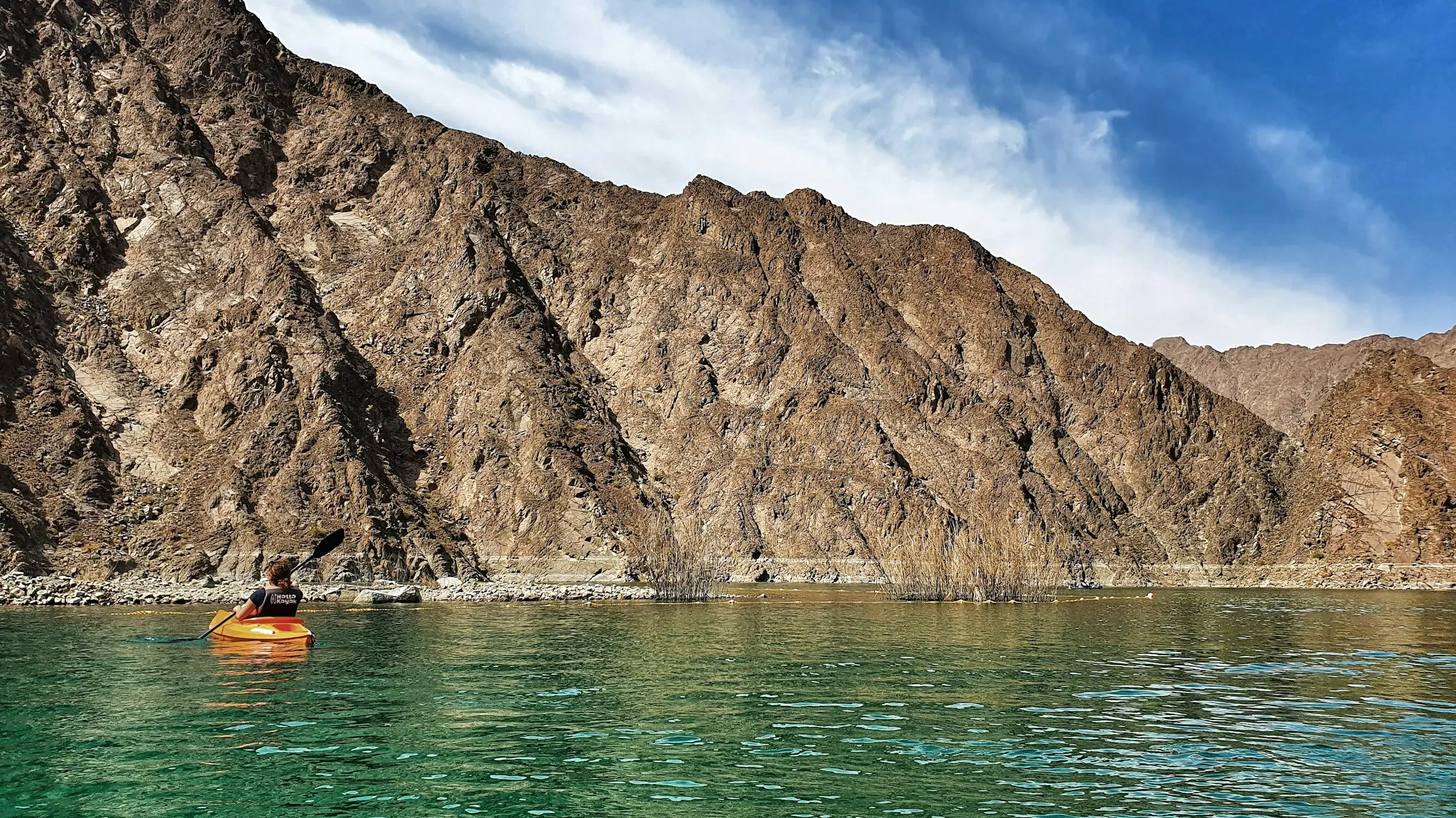 A kayaker on the turquoise water of Hatta Dam below the Hajar Mountains