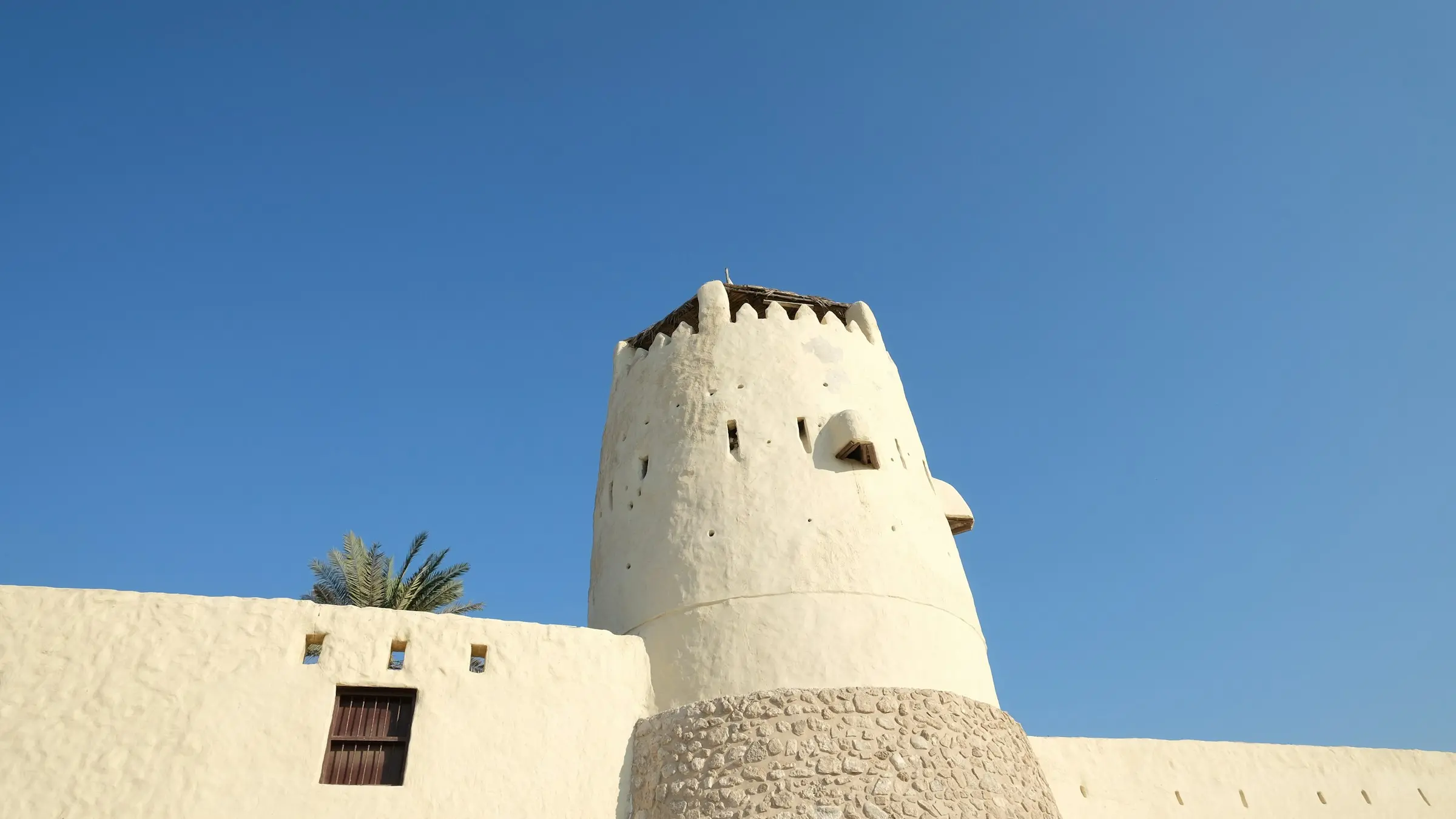 The white tower of Umm Al Quwain Fort against a clear blue sky