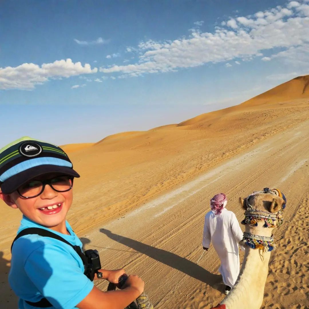 A child's camel ride on the desert safari, led by a guide