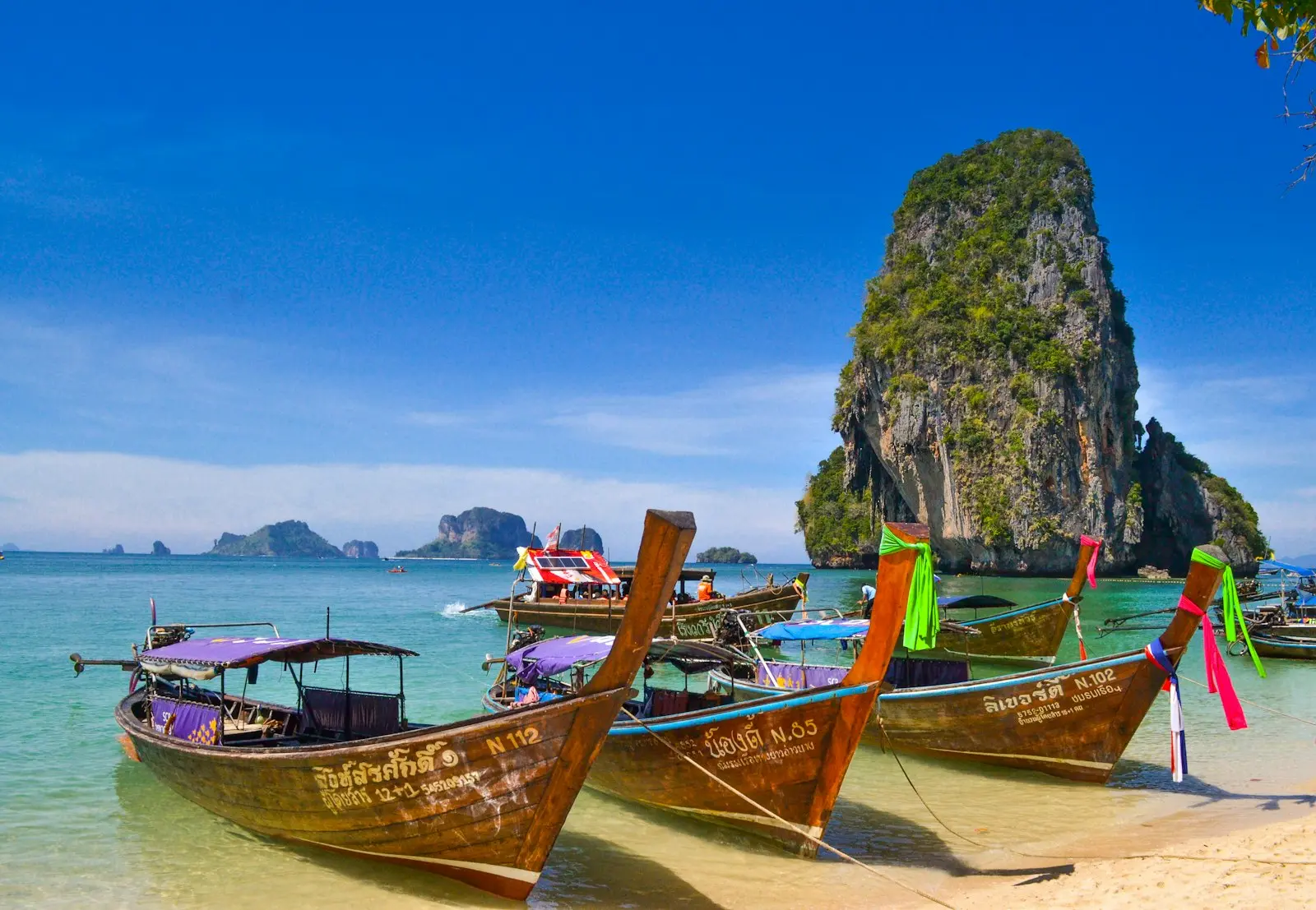 Longtail boats moored below limestone cliffs in Thailand